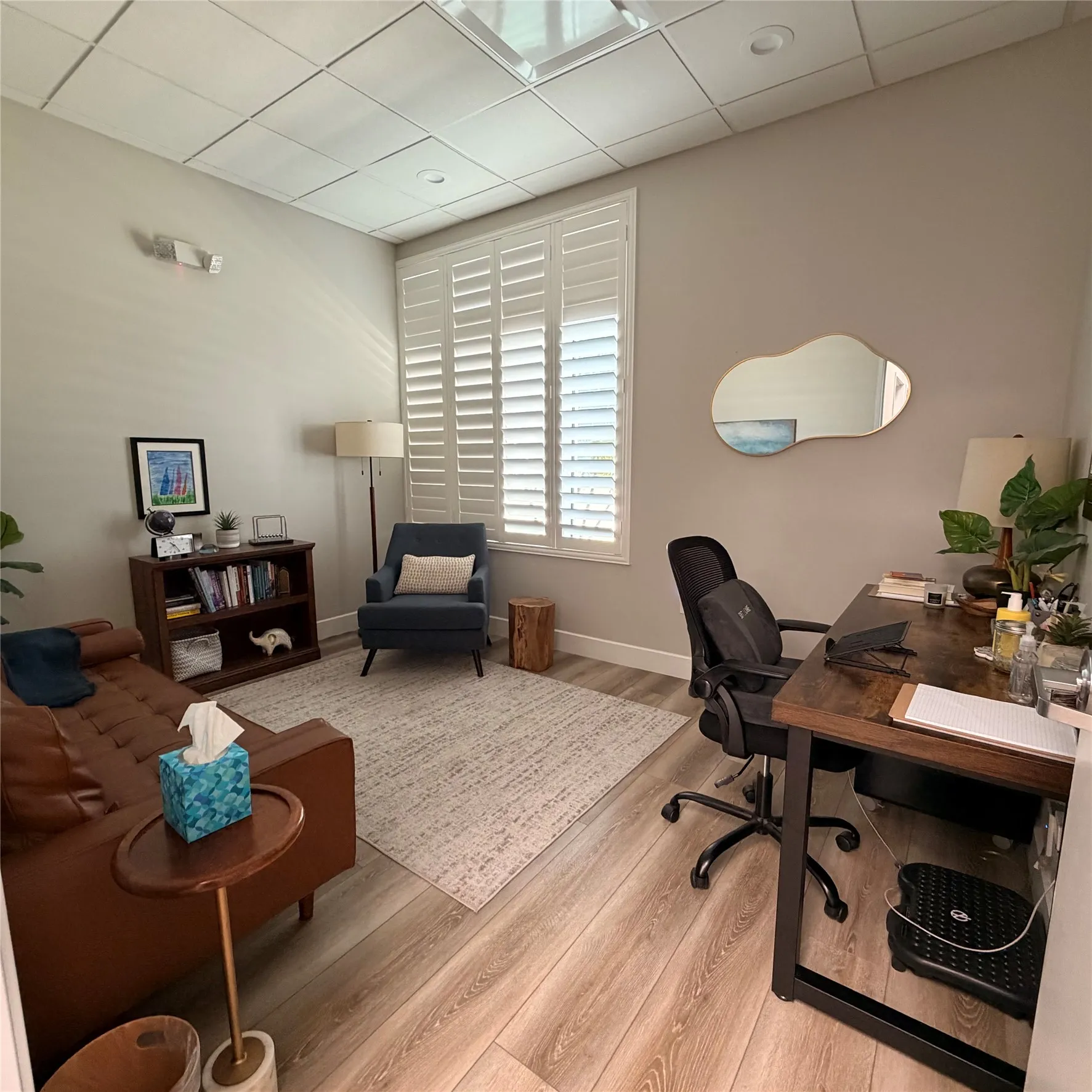 Room featuring wood-finish flooring, a neutral wall palette, and white plantation shutters