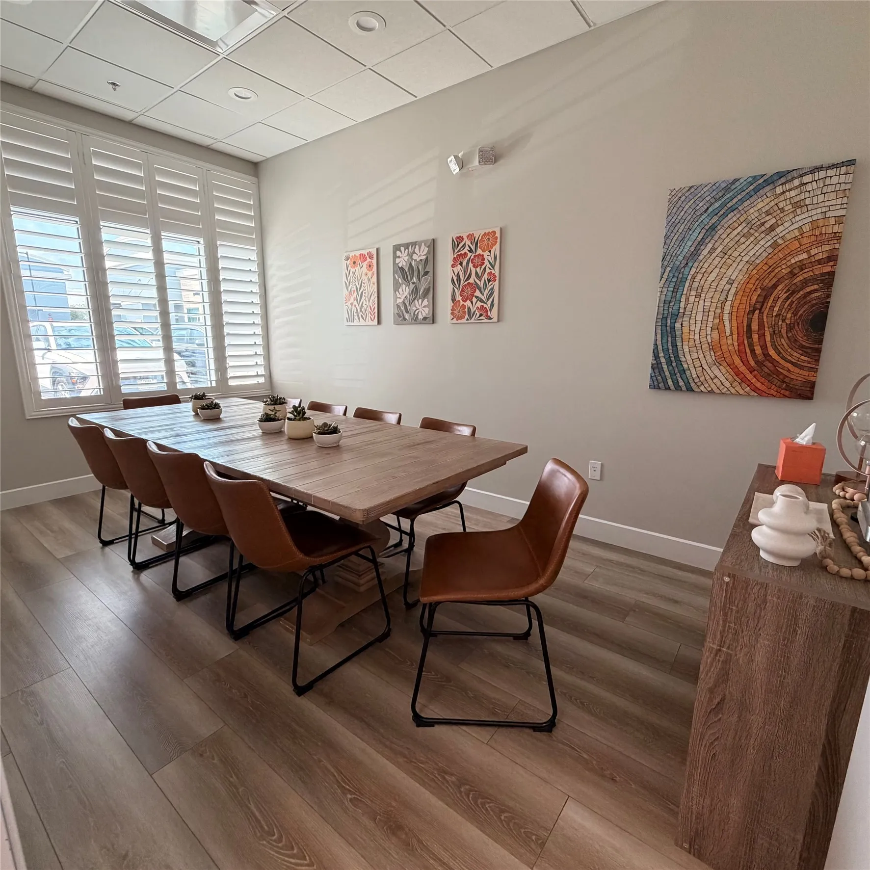 Spacious room featuring wood-finish flooring, plantation shutters, and a suspended ceiling with recessed lighting