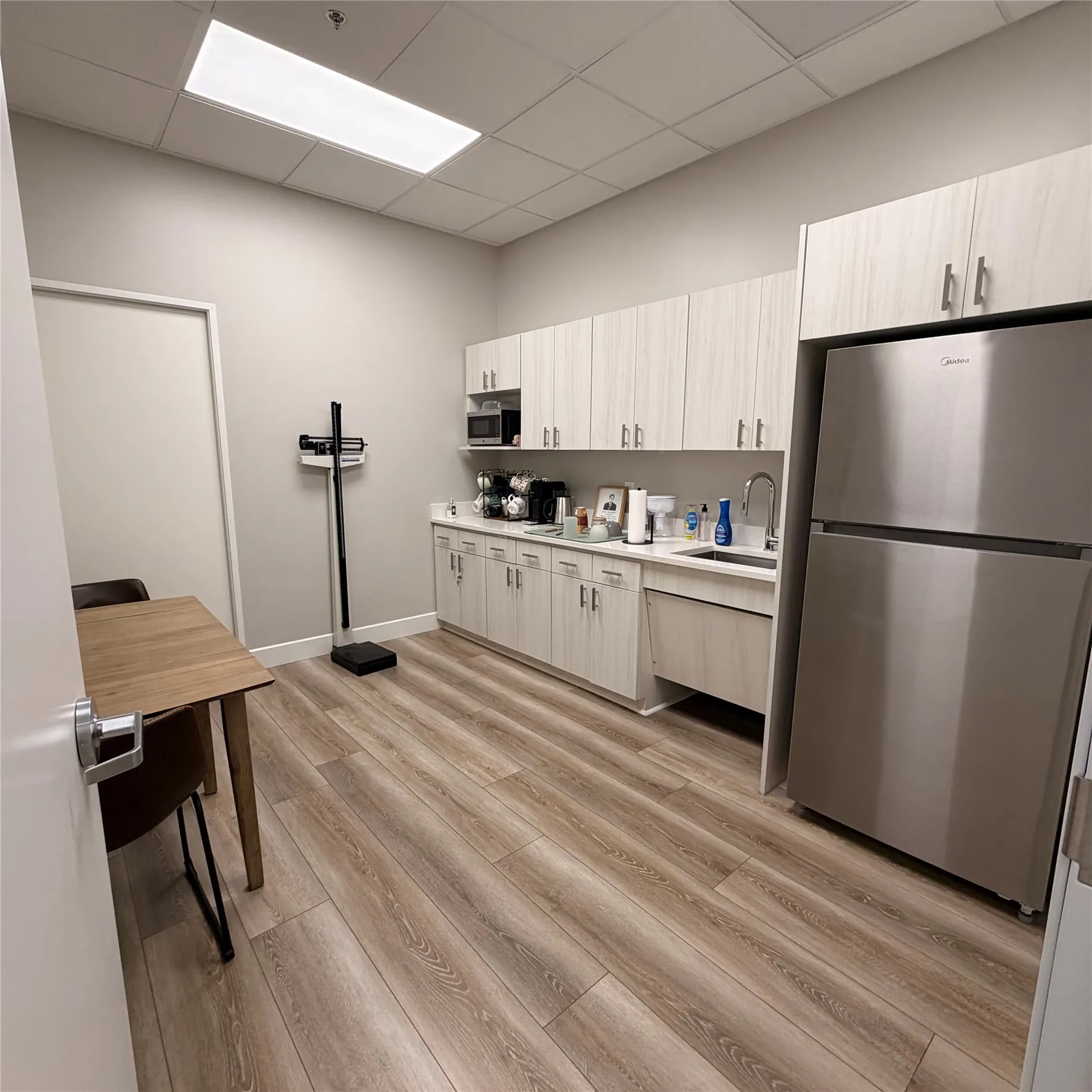 Dedicated kitchen area featuring extensive cabinetry, a built-in stainless steel refrigerator, and wood-finish flooring