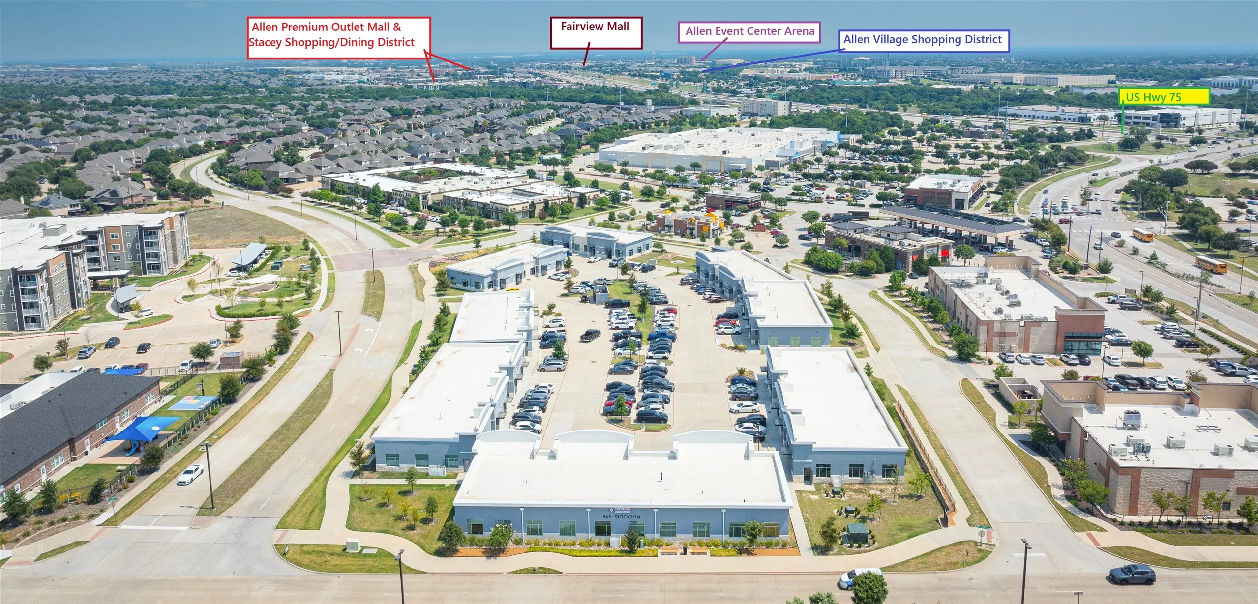 Aerial perspective showcasing a commercial development with multiple single-story and multi-story buildings, surrounded by extensive asphalt parking areas