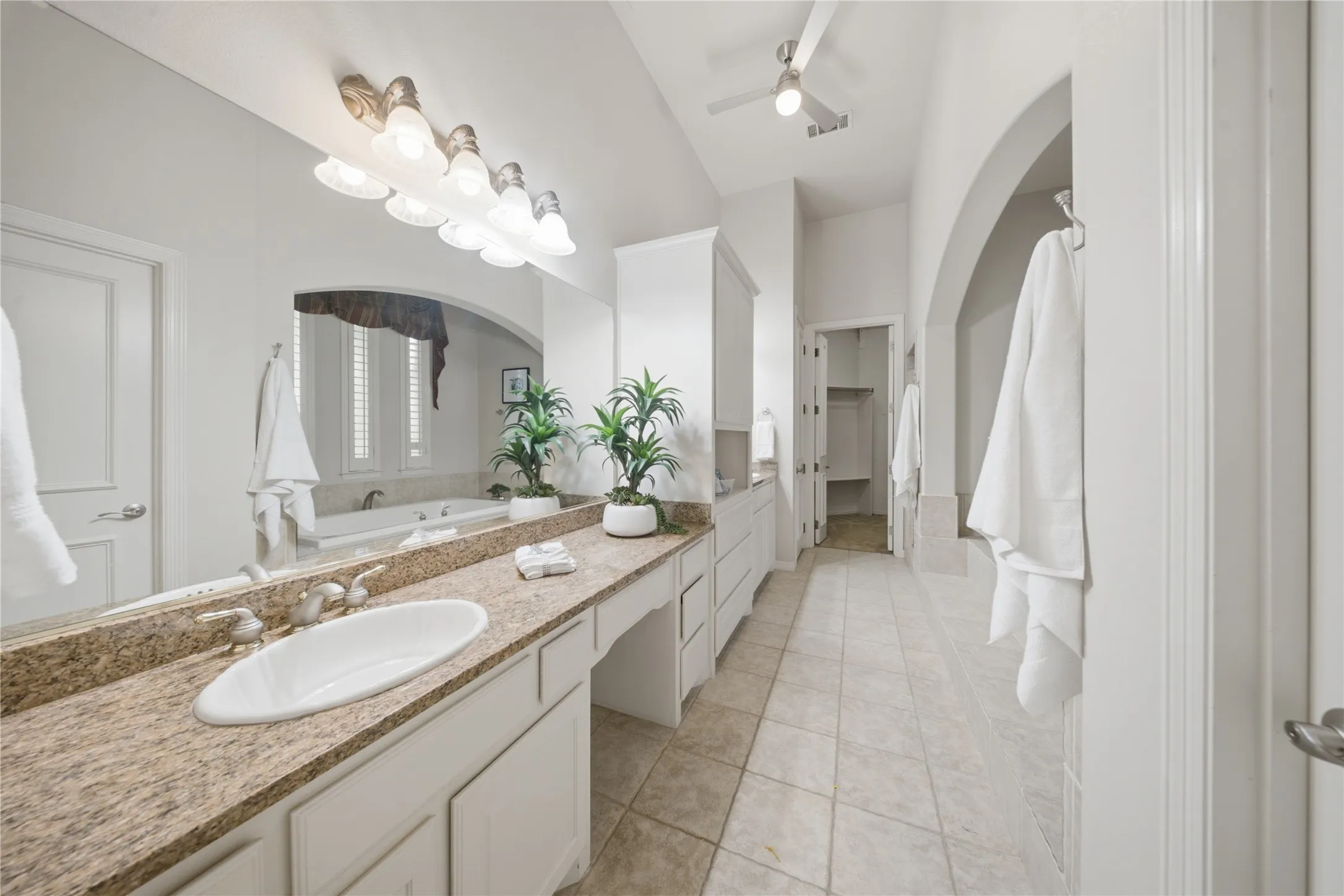 Spacious bathroom featuring a double vanity with stone countertops, a full-width mirror, and an oval undermount sink