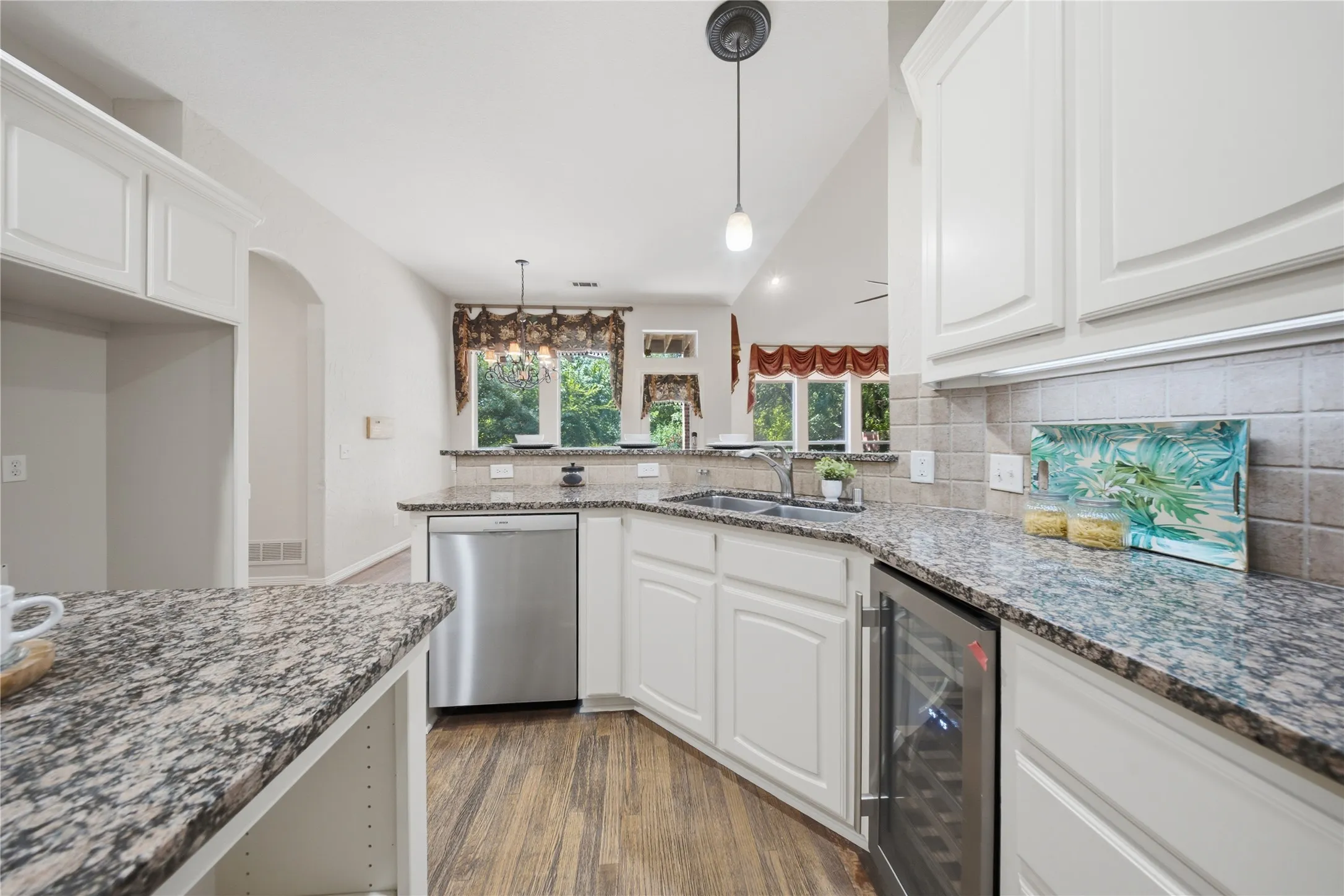 Kitchen featuring wood-finish flooring, white cabinetry, granite countertops, and a tile backsplash