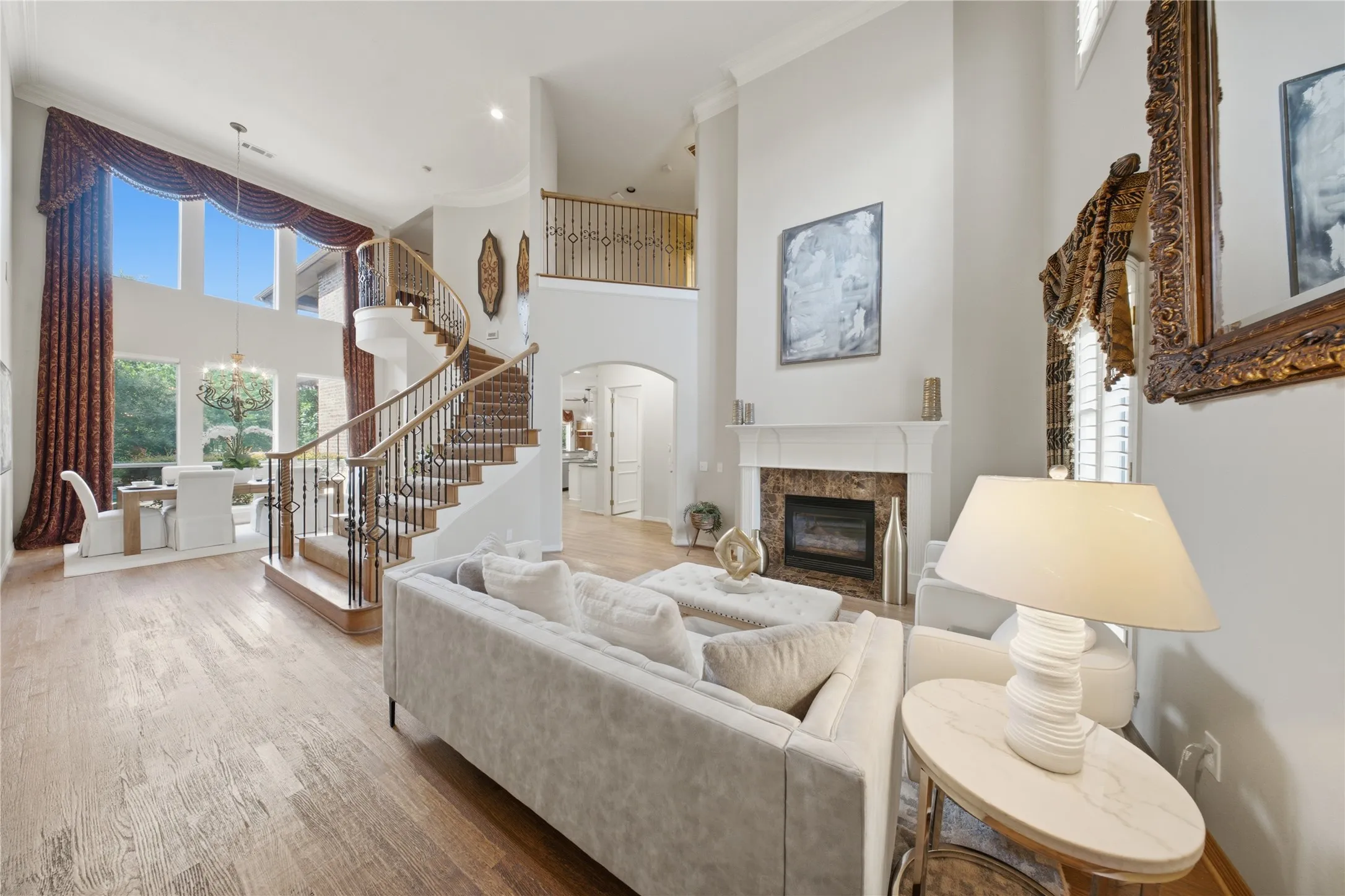Open-concept living space featuring high ceilings, wood-finish flooring, and a two-story fireplace with a stone surround