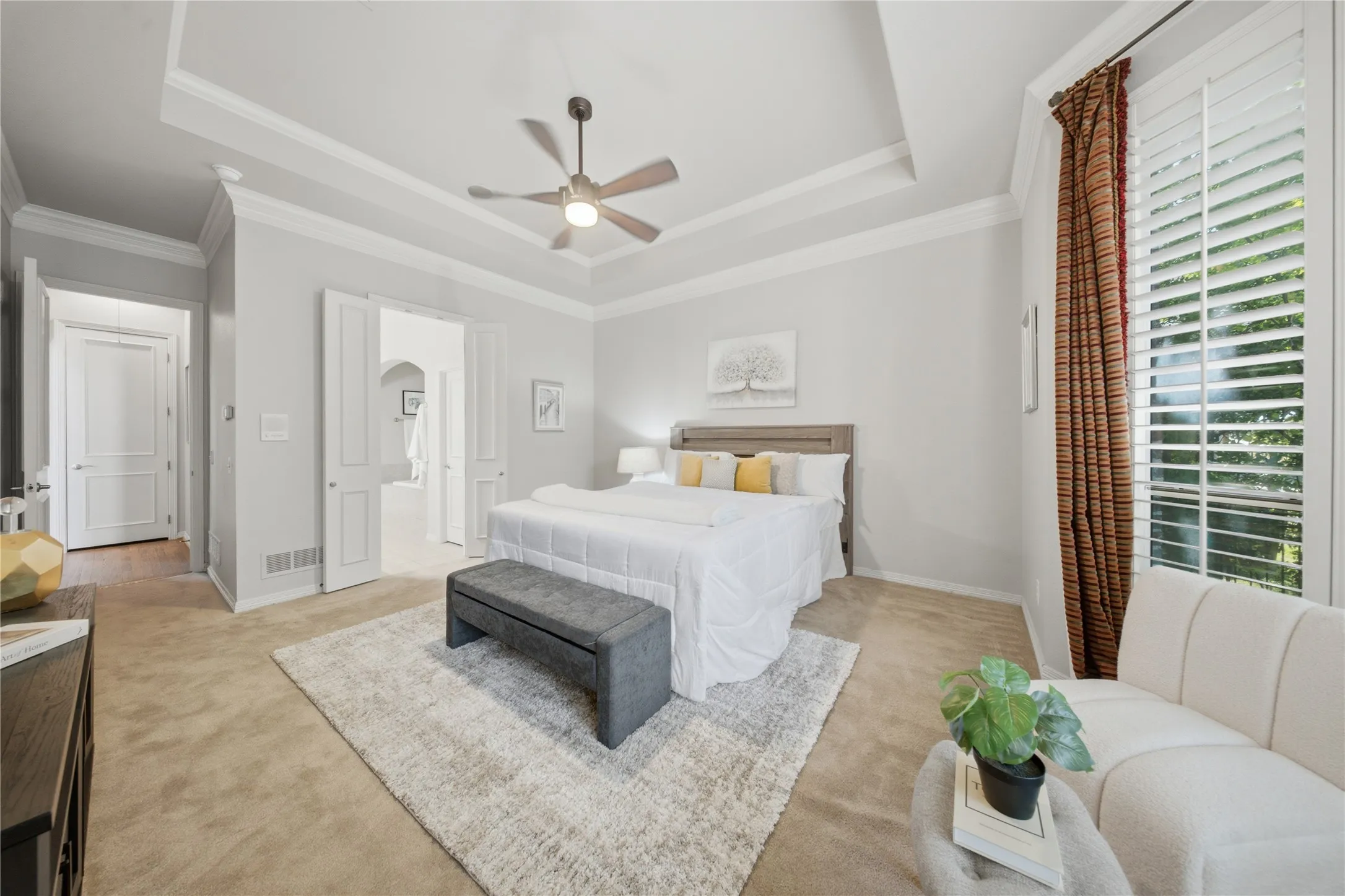 Tray ceiling with crown molding, double door entry, plantation shutters, recessed lighting, and wood-finish flooring in the doorway