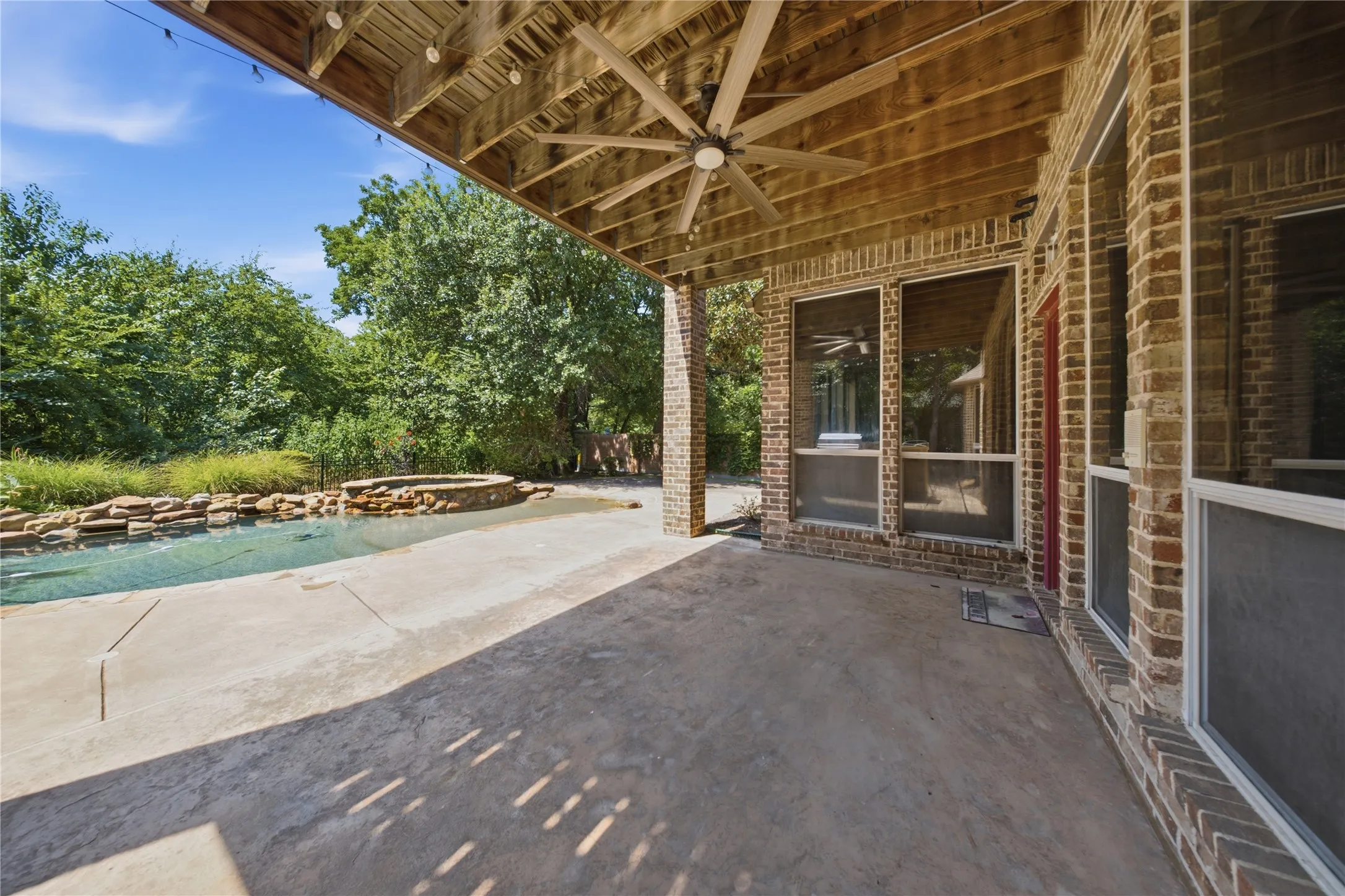 Expansive covered patio with exposed wood ceiling and ceiling fan