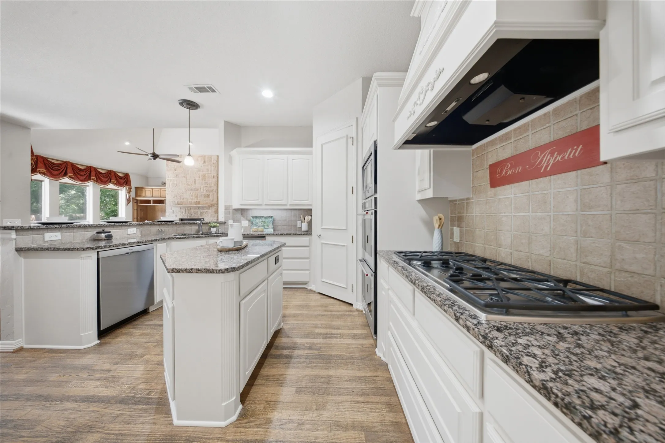 Kitchen featuring white cabinetry, wood-finish flooring, granite countertops, a built-in gas range, and double wall ovens