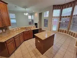 Kitchen featuring wood-finish cabinetry, stone countertops, and tile flooring