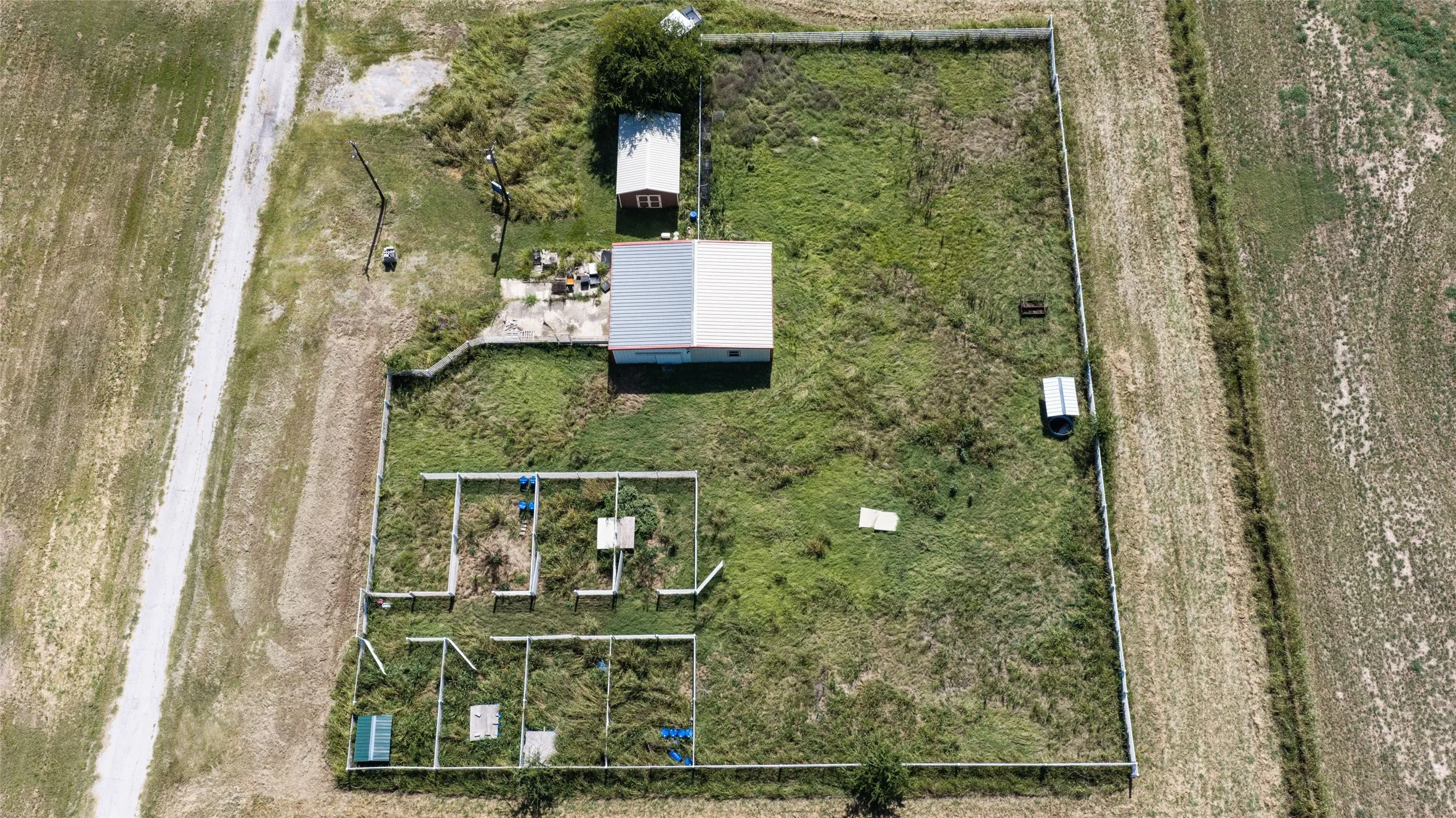 Bird's-eye view showcasing the thoughtfully designed livestock facilities with fenced pens, a loafing shed, storage building, and ample space for caring for a variety of animals