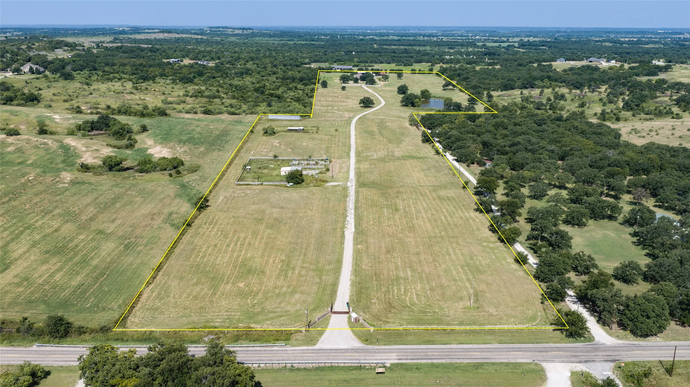 Extensive rural property featuring a private pond, mature trees, and a long driveway leading to the main residence