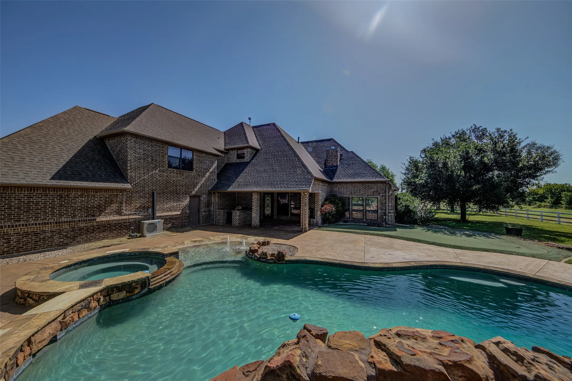 Freeform swimming pool with integrated spa and rock waterfall feature