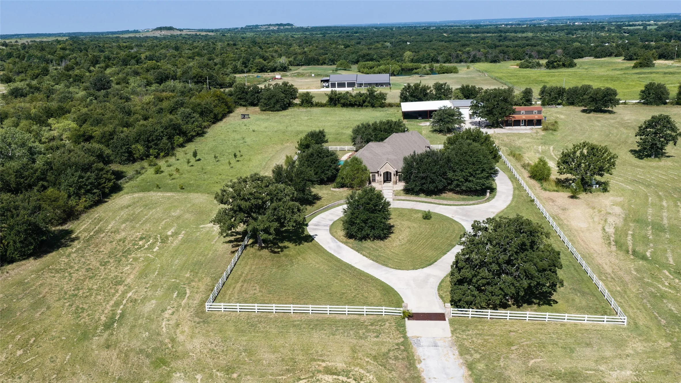 Extensive rural property featuring a private pond, mature trees, and a long driveway leading to the main residence
