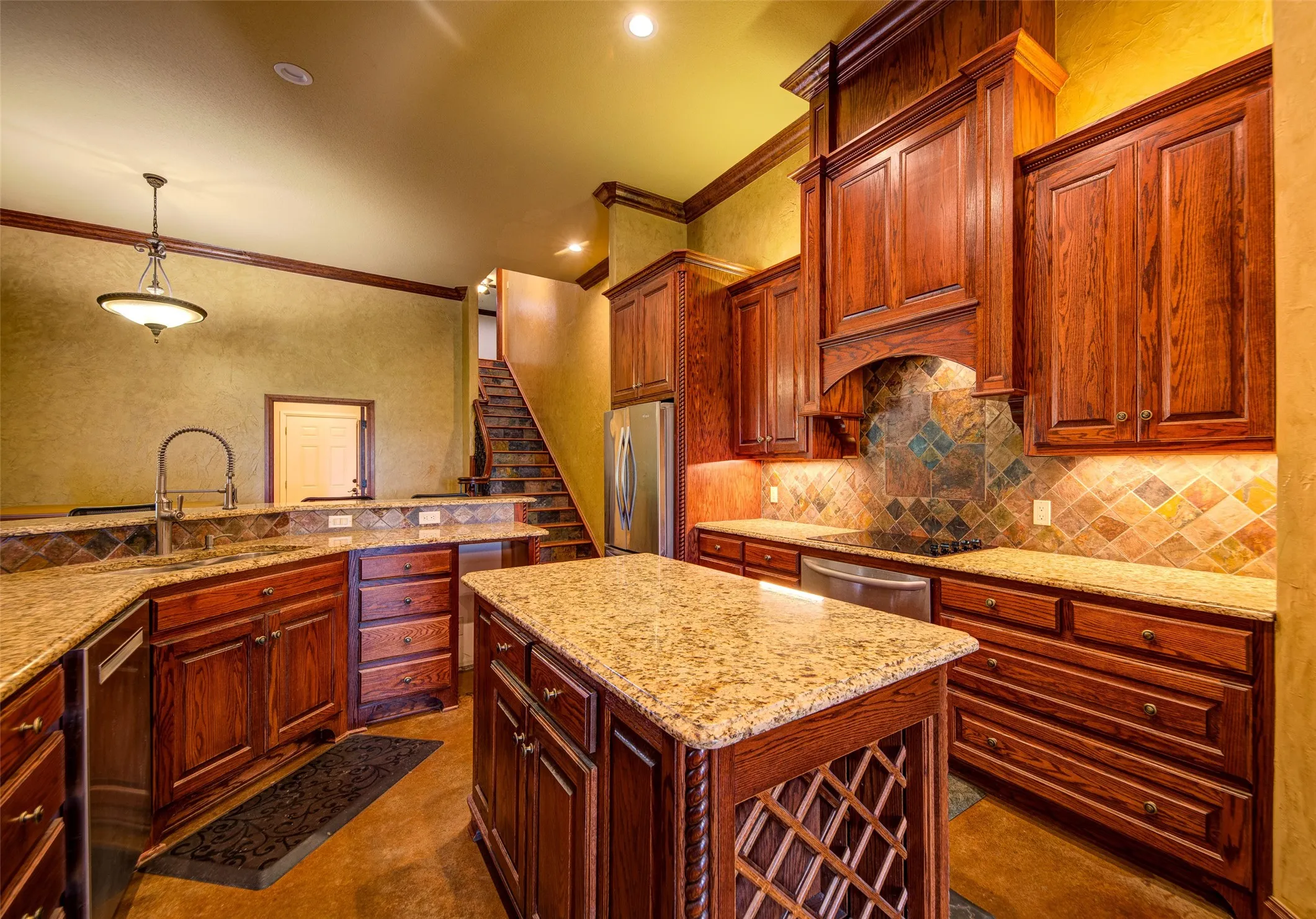 Expansive kitchen featuring wood cabinetry, stone countertops, and a decorative tile backsplash