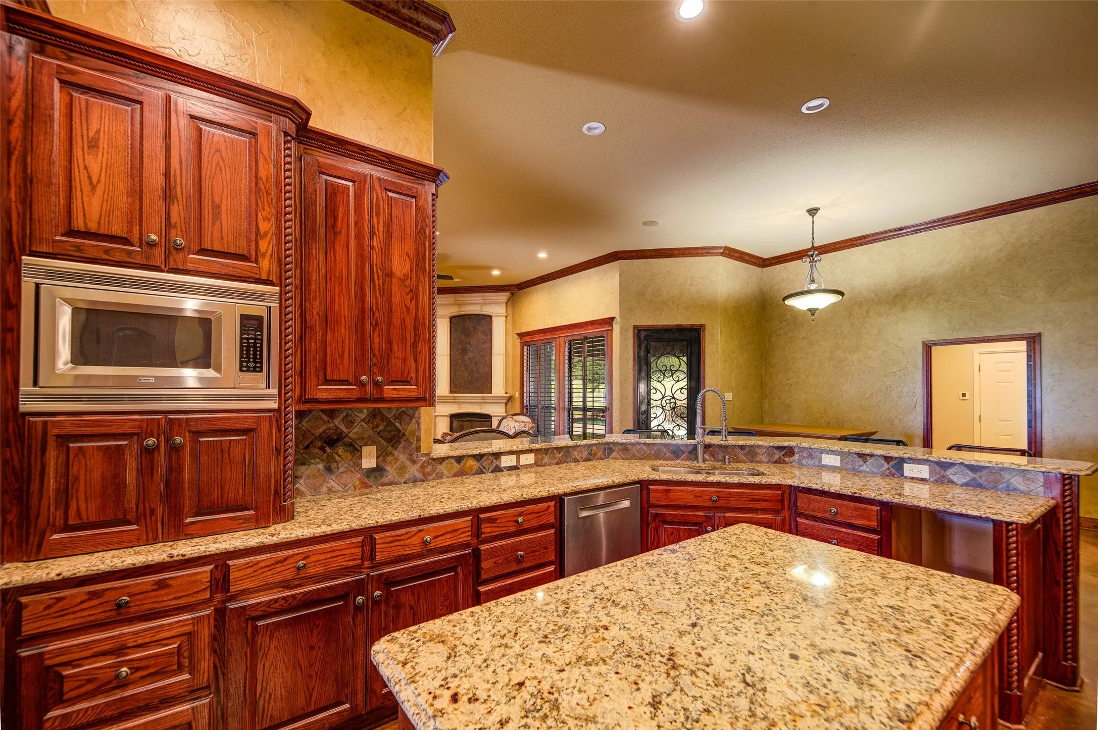 Gourmet kitchen featuring rich wood cabinetry, granite countertops, a central island with a built-in wine rack, a tile backsplash, and stainless steel appliances