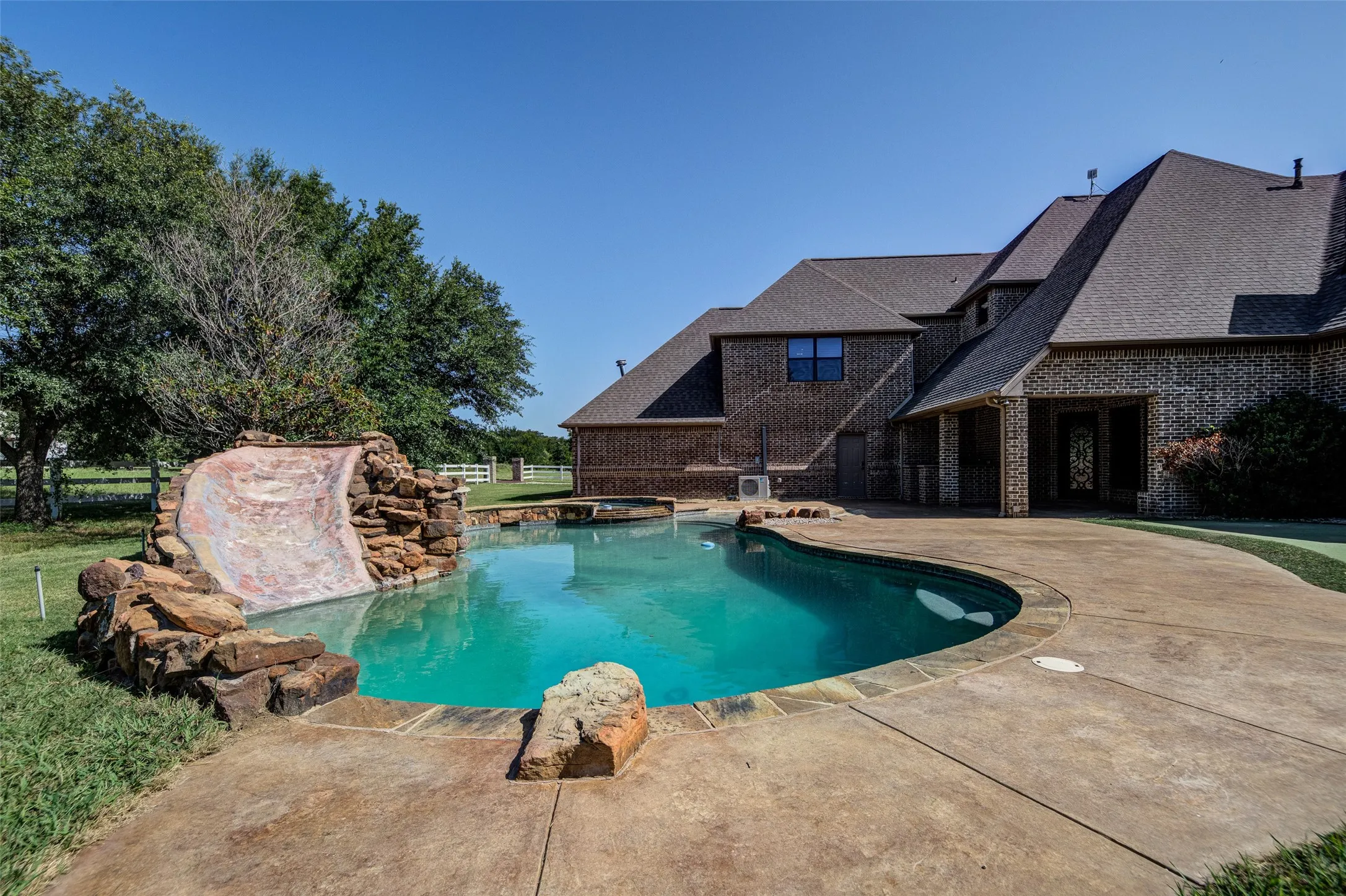 Two-story residence featuring a dark exterior, a covered front porch with wood columns, and a reddish-brown metal roof