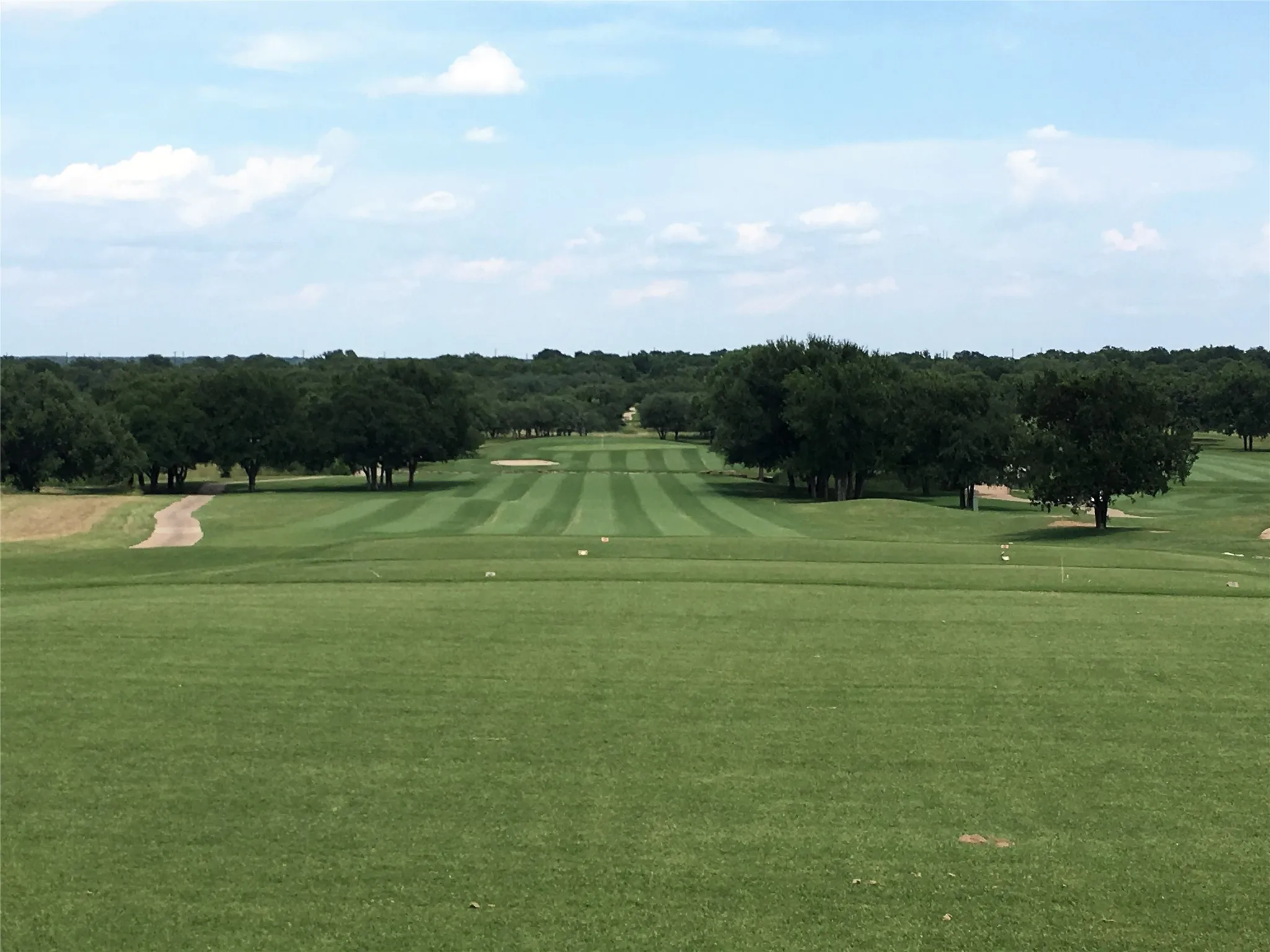 Expansive golf course featuring manicured fairways, mature tree lines, and sand bunkers