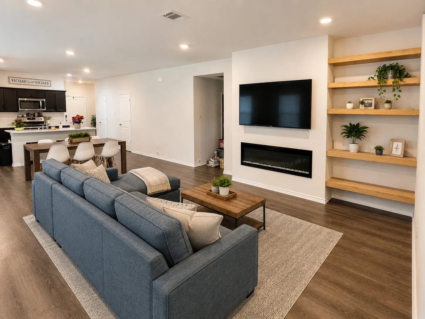 Open-concept living space featuring wood-finish flooring, recessed lighting, and a built-in electric fireplace