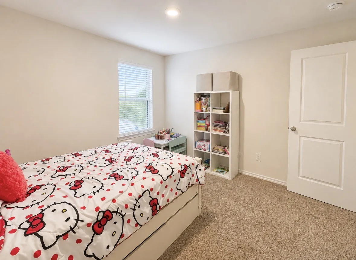 Neutral-toned room with plush carpet flooring, a window with blinds, and white trim