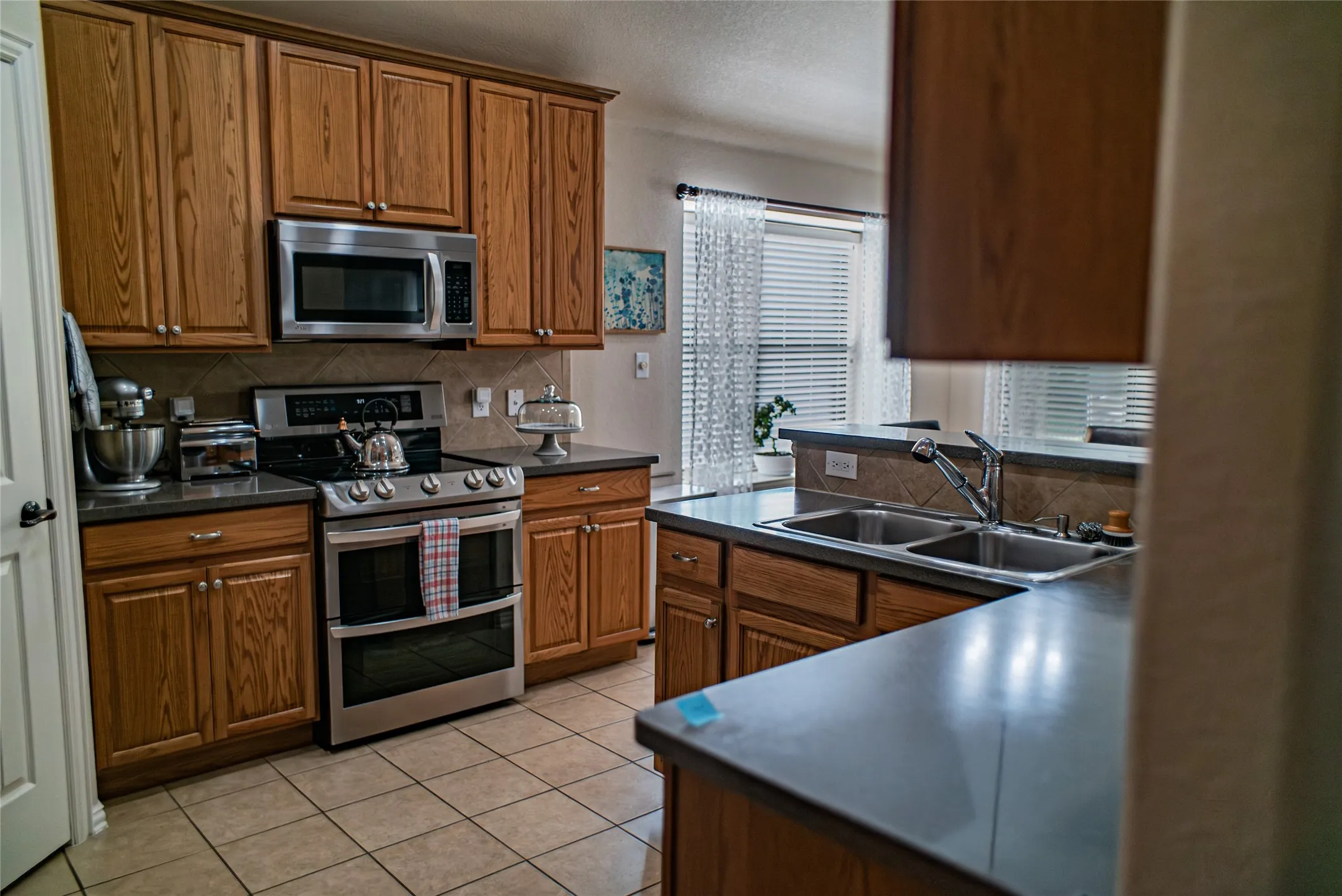 Kitchen featuring wood-finish cabinetry, stainless steel appliances, and a double basin sink