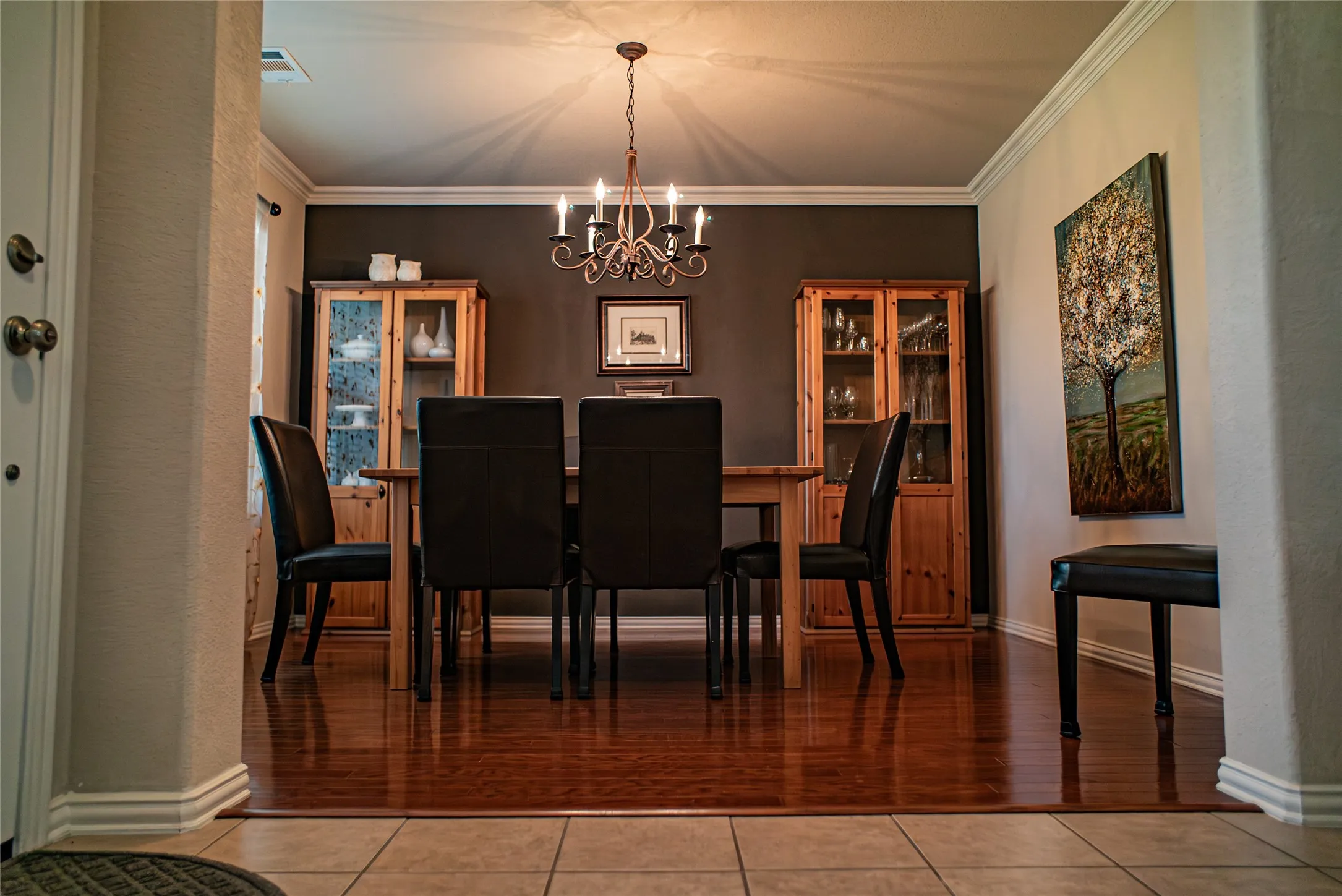 Hardwood-finish flooring highlights this dining area, featuring a decorative chandelier and crown molding