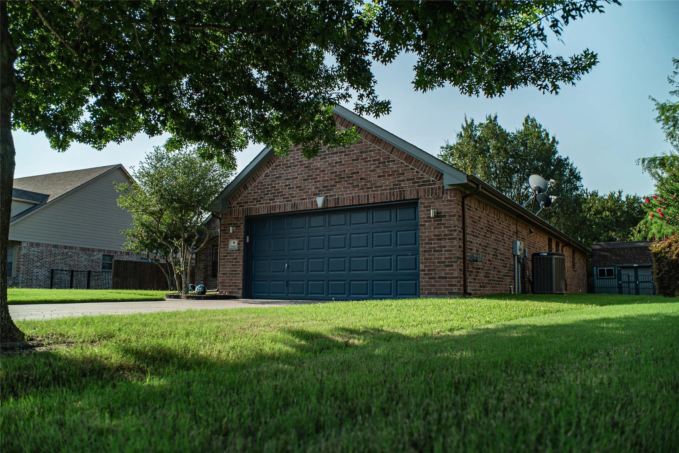Brick exterior featuring a two-car garage with a paneled door, pitched roof, and concrete driveway