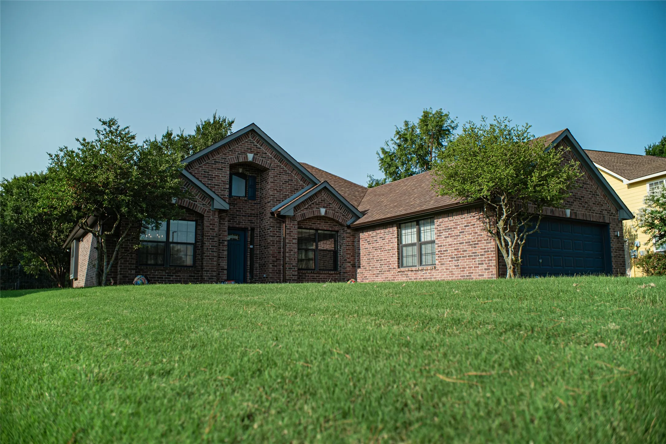 Brick exterior residence featuring a dark blue garage door and front entry door