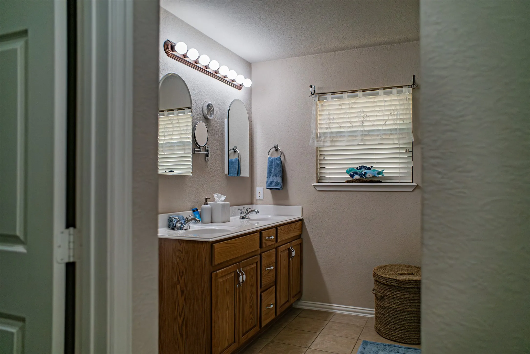 Double vanity with wood-finish cabinetry, dual undermount sinks, and a white countertop