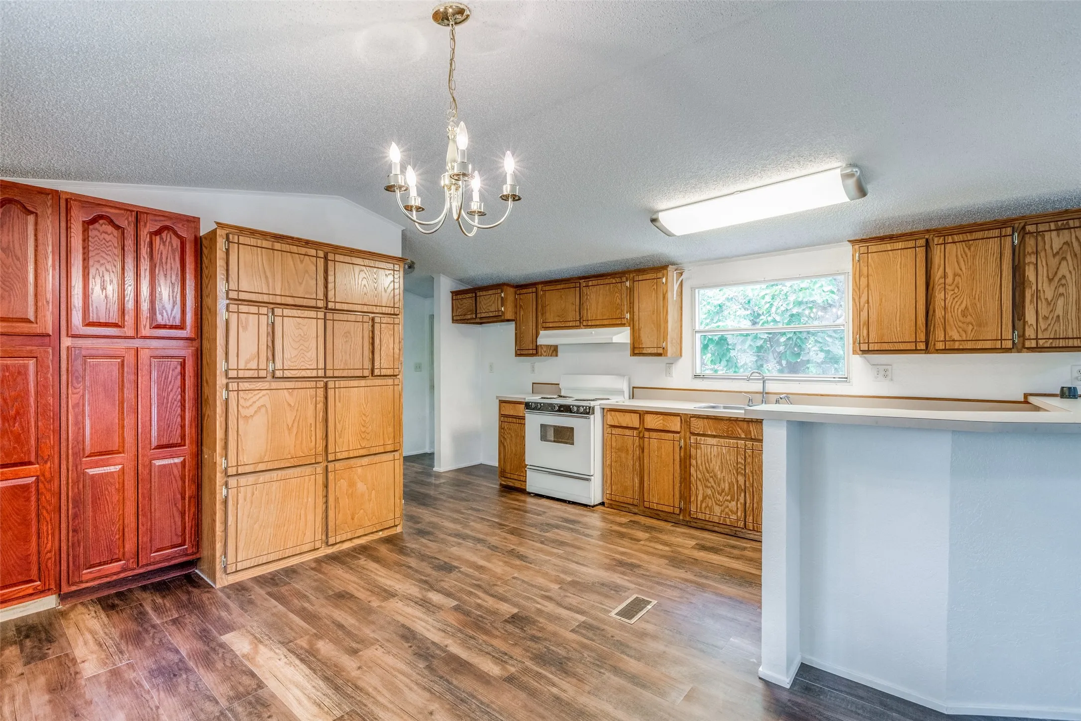 Kitchen with dark hardwood/wood-style flooring, stainless steel sink and lofted ceiling.