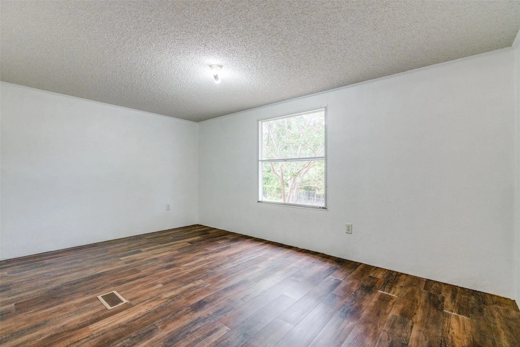 Large secondary bedroom with dark hardwood/wood-style floors and a beautiful view.