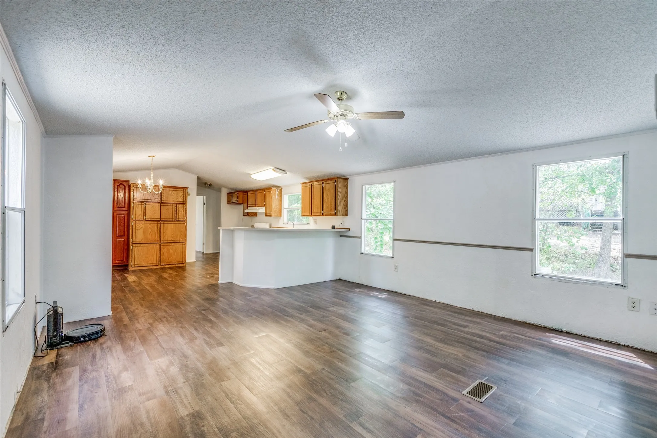 Large family room with dark wood-type flooring, a textured ceiling, lofted ceiling and a healthy amount of sunlight.