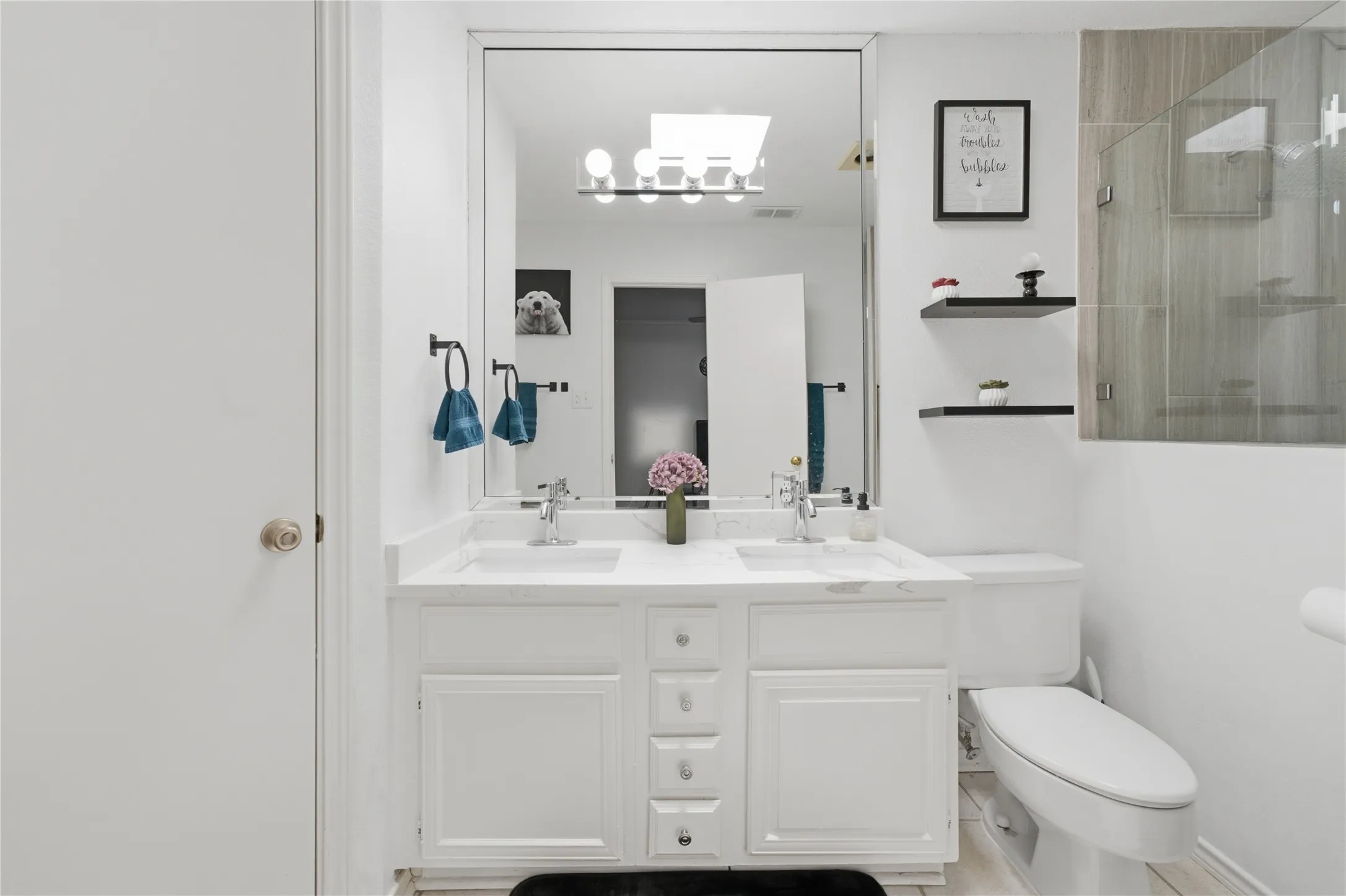 Bathroom vanity featuring dual undermount sinks, chrome faucets, and white cabinetry with storage drawers