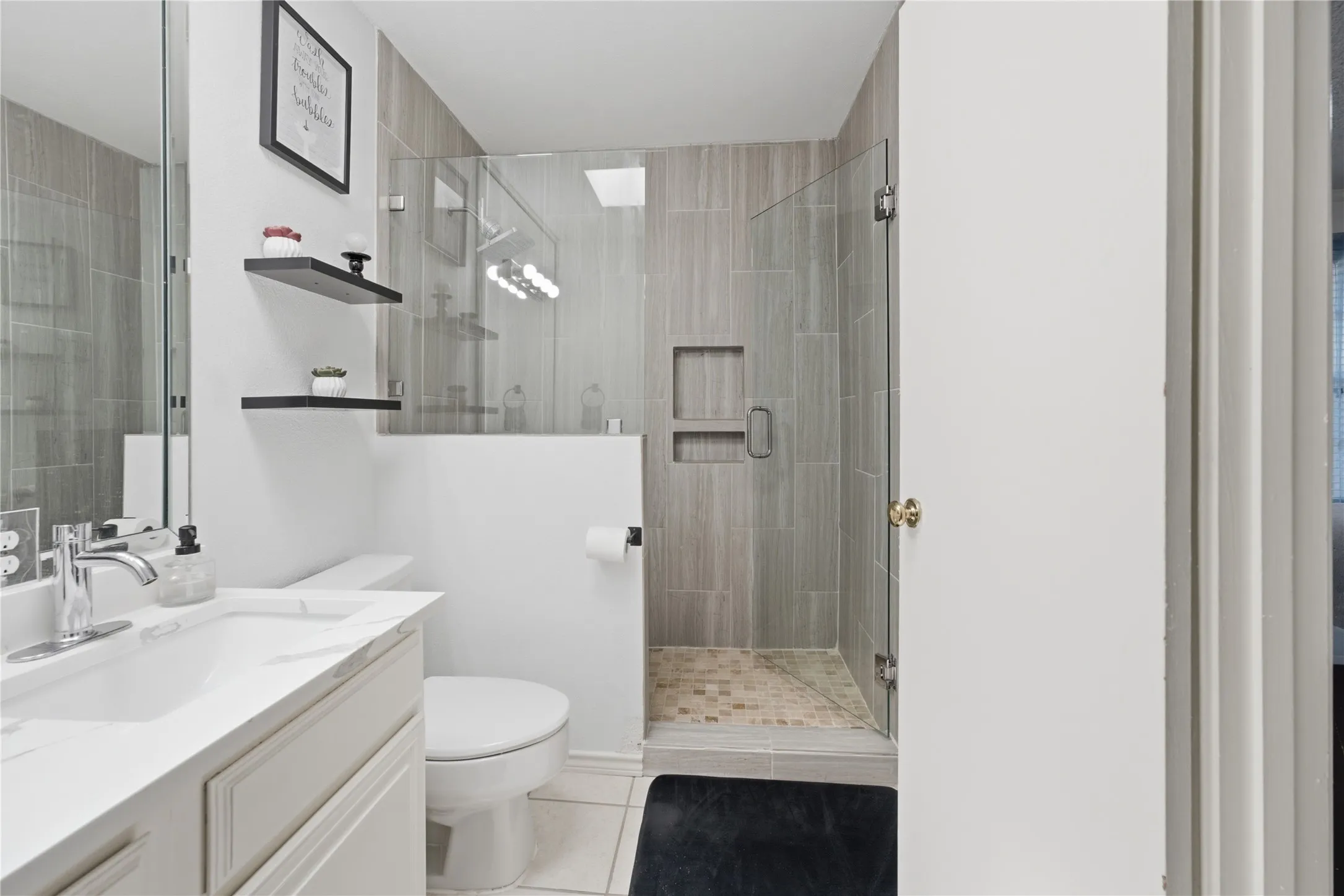 Bathroom featuring a glass-enclosed shower with tile surround and recessed niche
