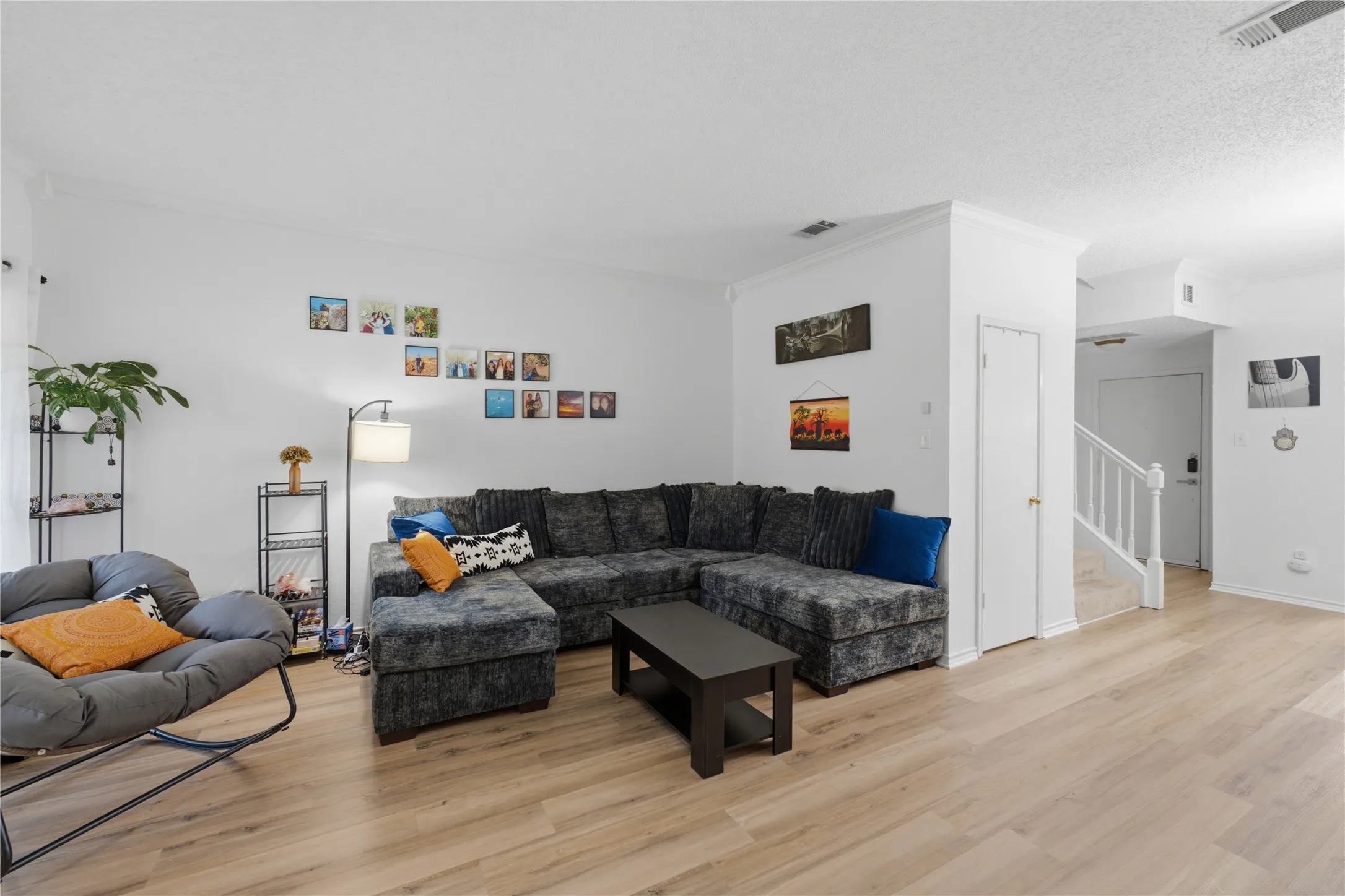 Open-concept living area featuring light wood-finish flooring, white walls, and a staircase with white balusters