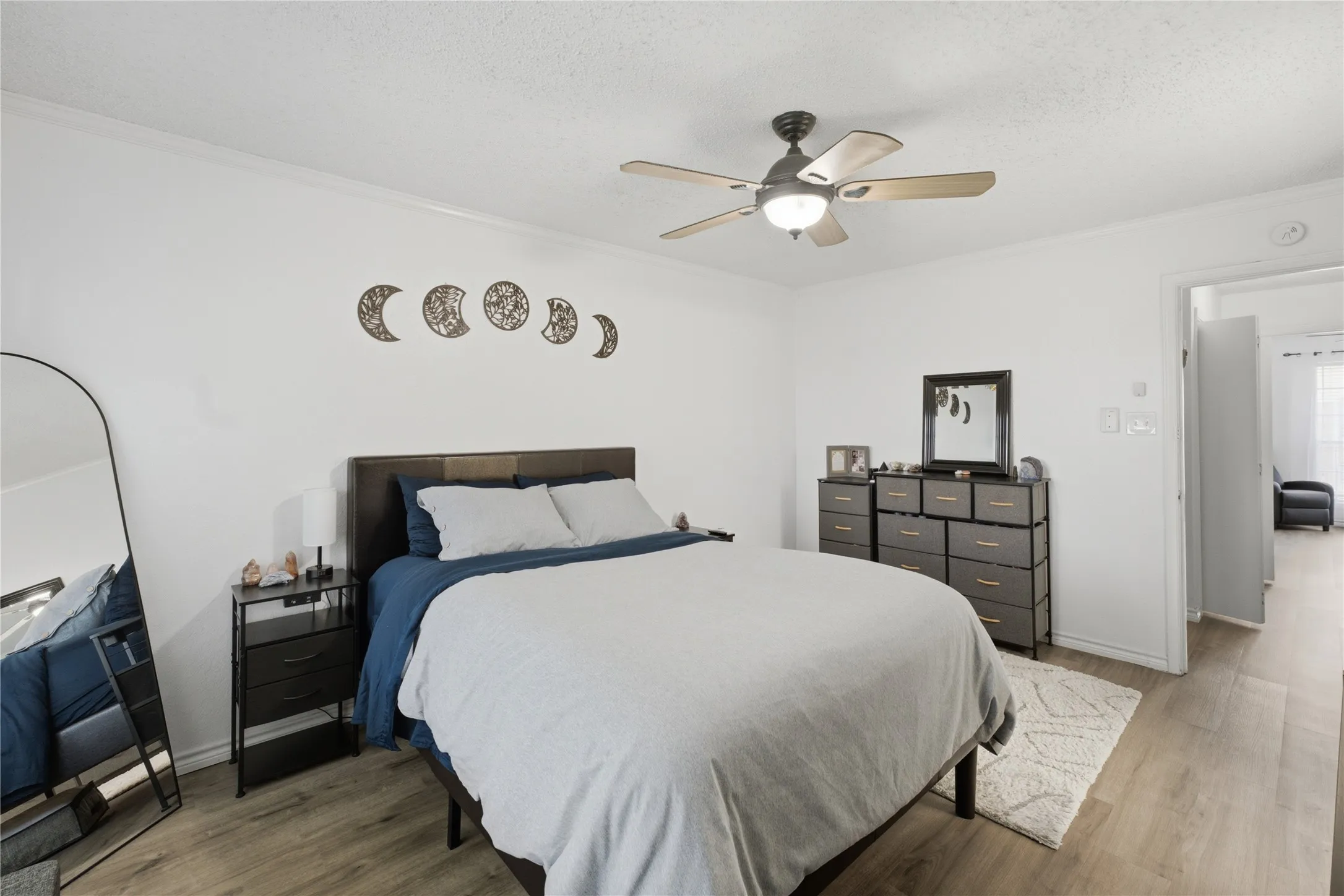 Bright room featuring wood-finish flooring, a ceiling fan with integrated lighting, and white baseboards