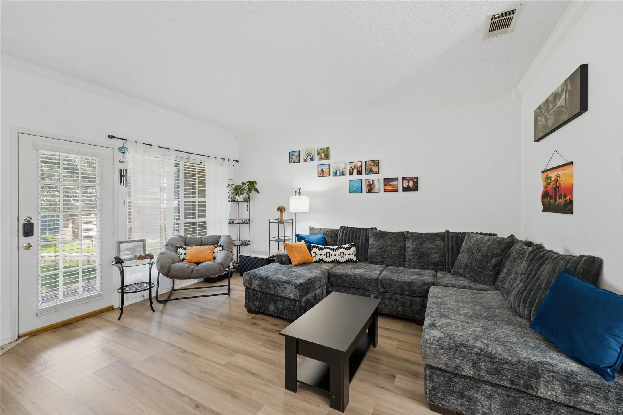 Bright living area featuring wood-finish flooring, white walls, and crown molding