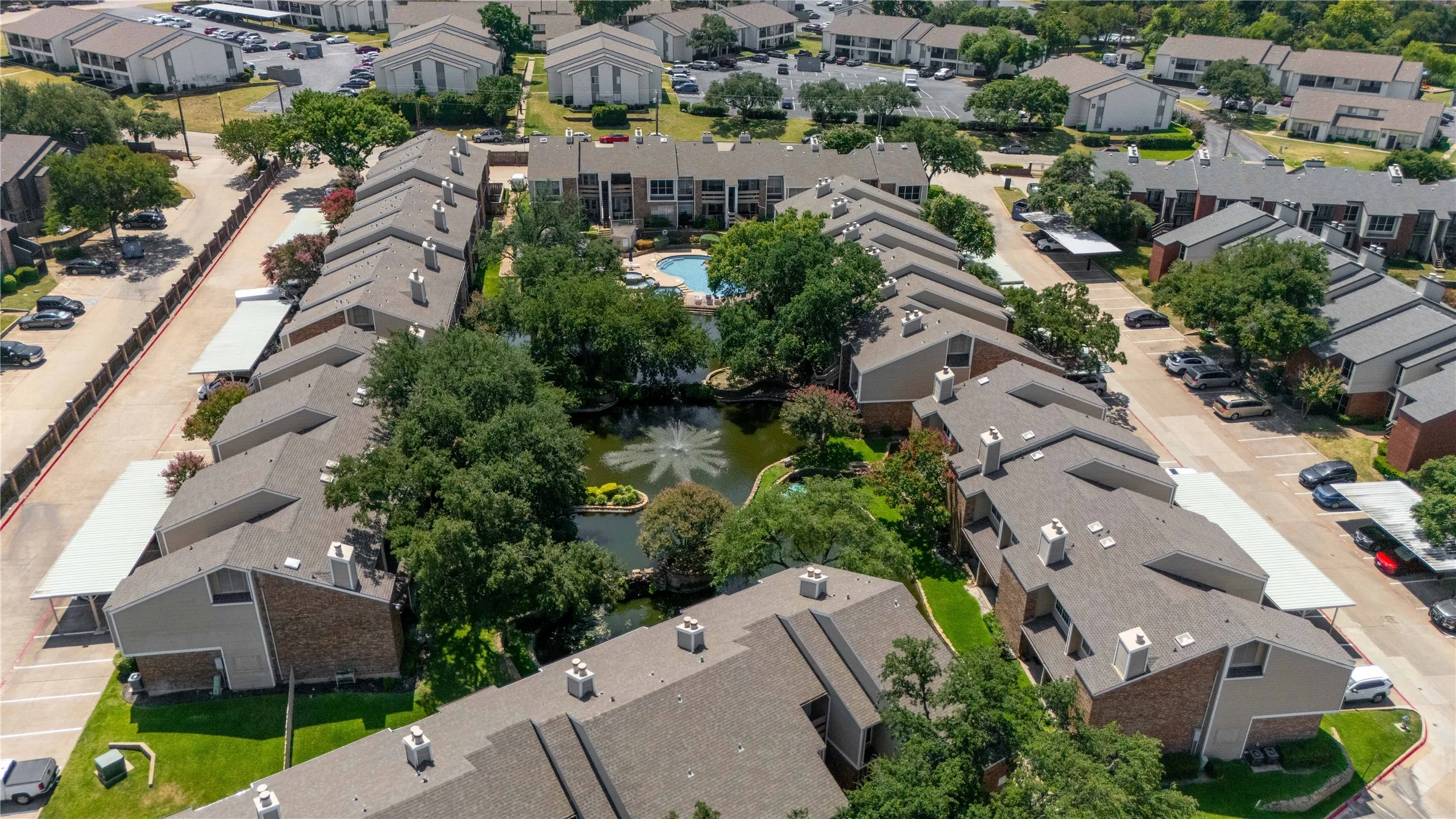 Aerial perspective showcasing a multi-unit property with a central pond featuring a fountain