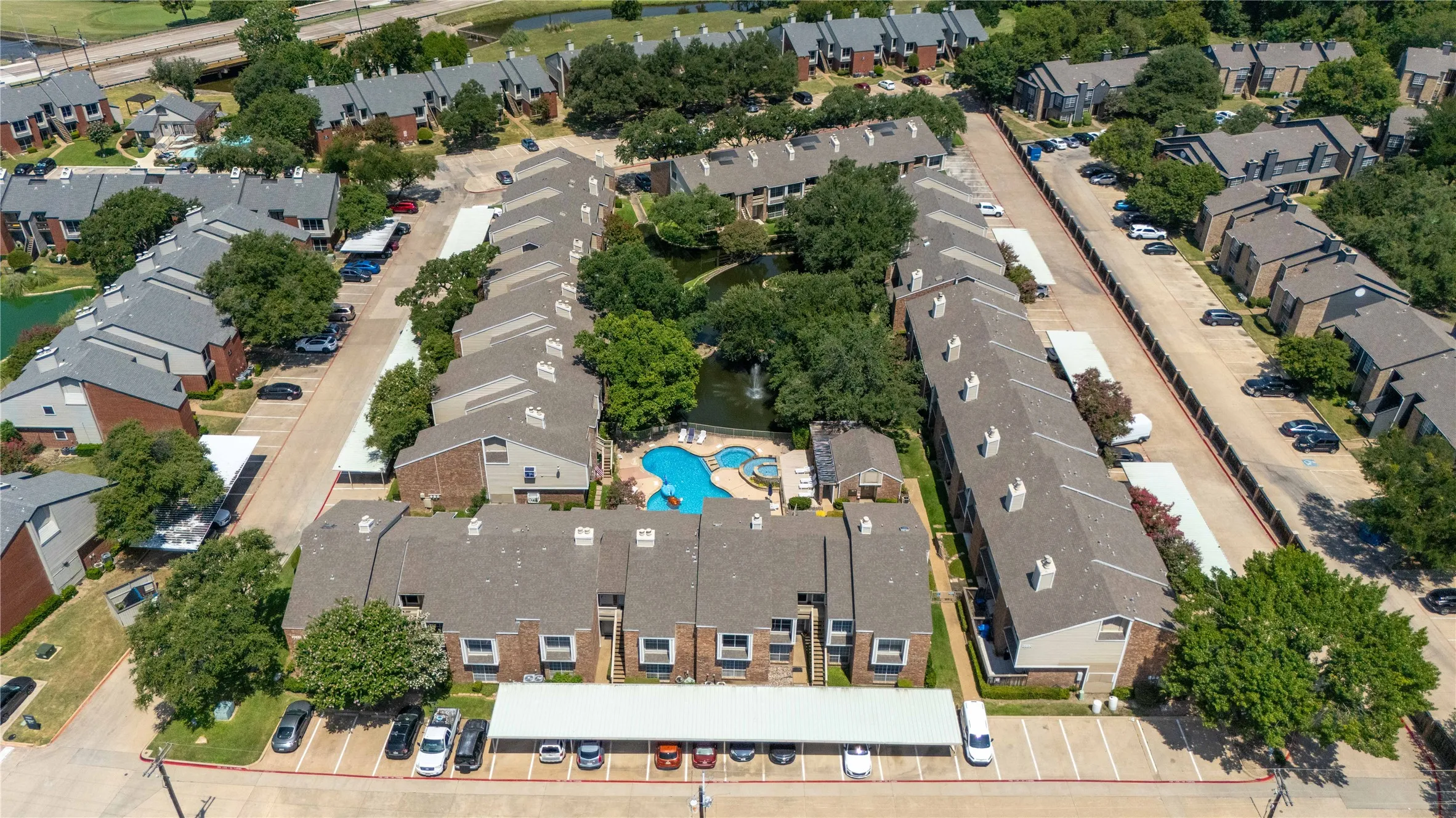 Aerial view showcasing a multi-building property featuring a central courtyard with a swimming pool and a pond with a fountain