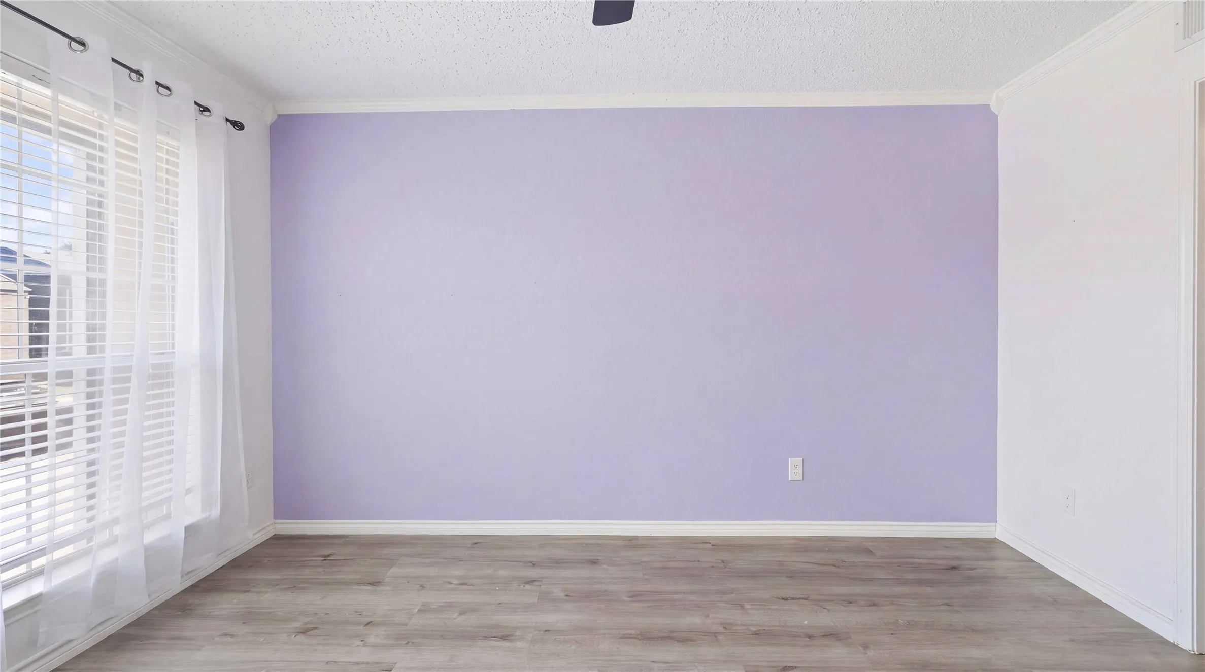 Wood-finish flooring, textured ceiling, ceiling fan, and window with blinds