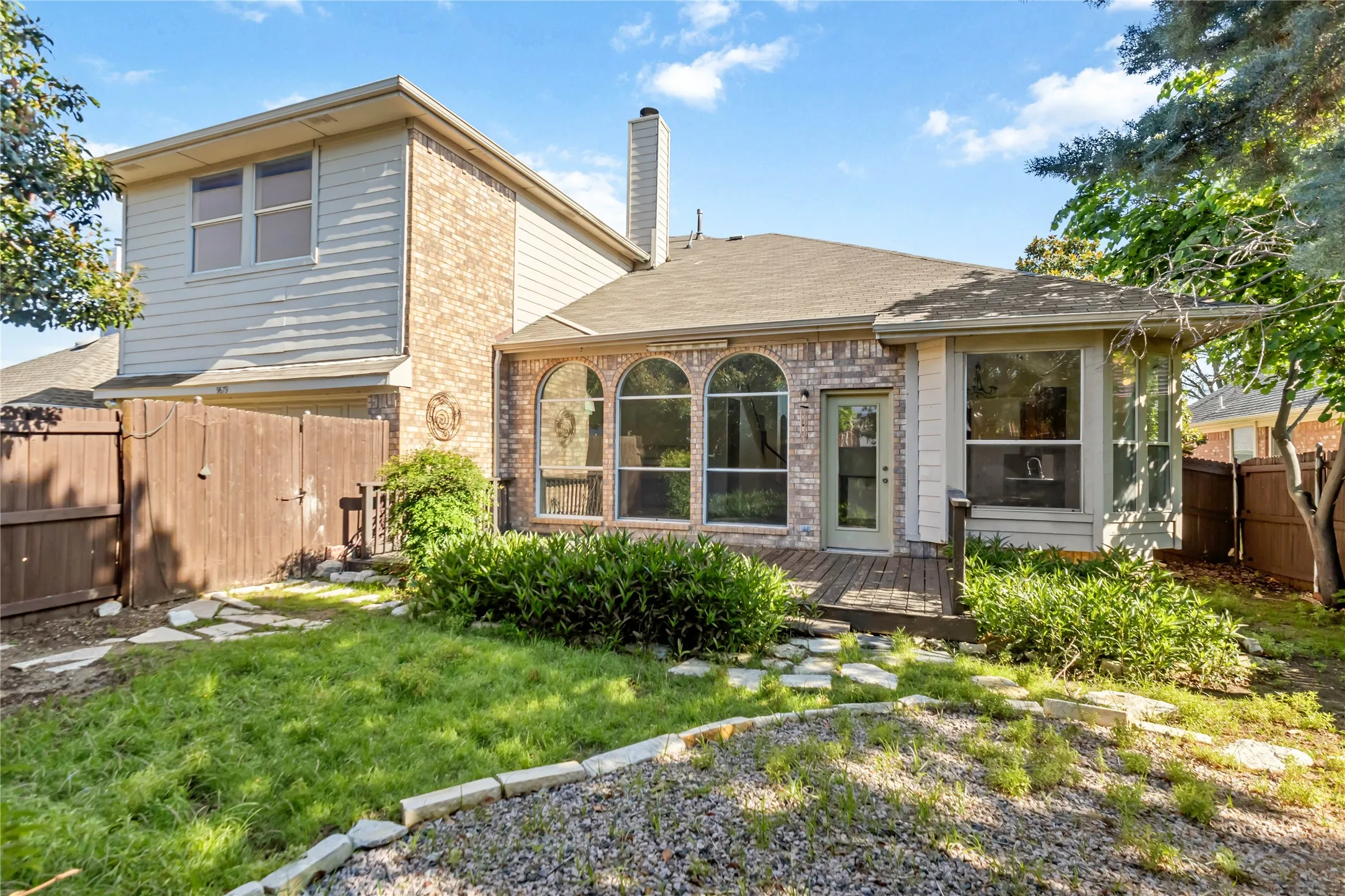 Brick exterior with siding accents, arched windows, and a wood deck