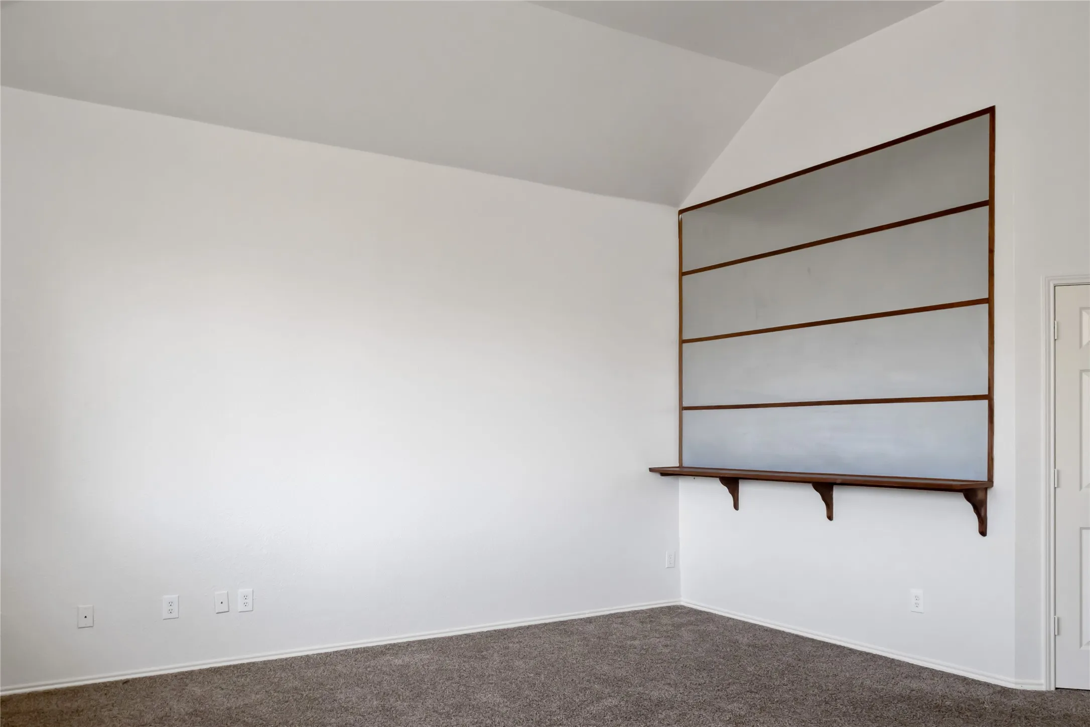 Vaulted ceiling, built-in shelving, wood-finish countertop, white walls, and gray carpeting