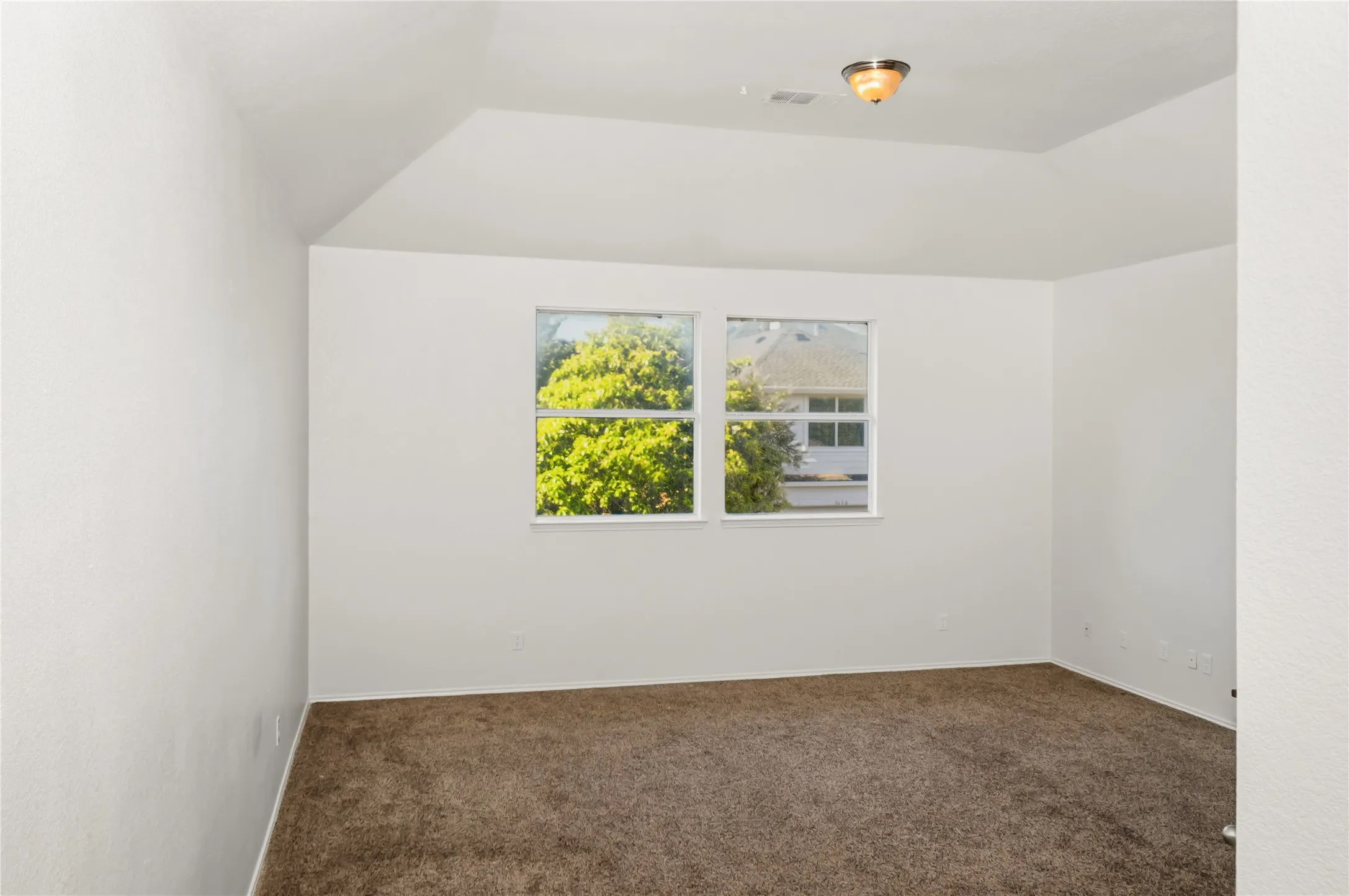 Vaulted ceiling, dual windows, neutral wall color, recessed lighting, carpet flooring