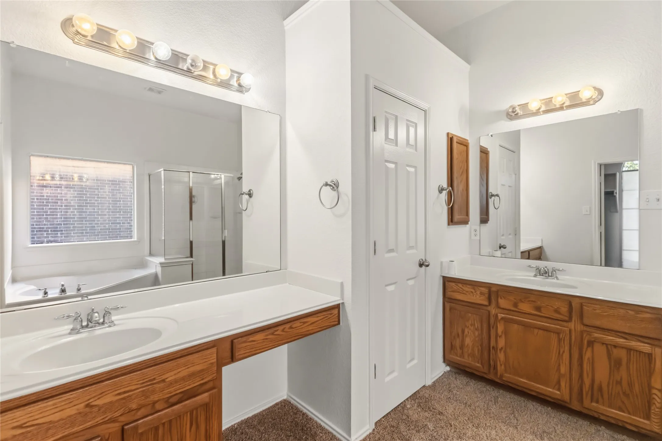 Dual wood-finish vanities with integrated sinks, expansive vanity mirrors, and wall-mounted light fixtures