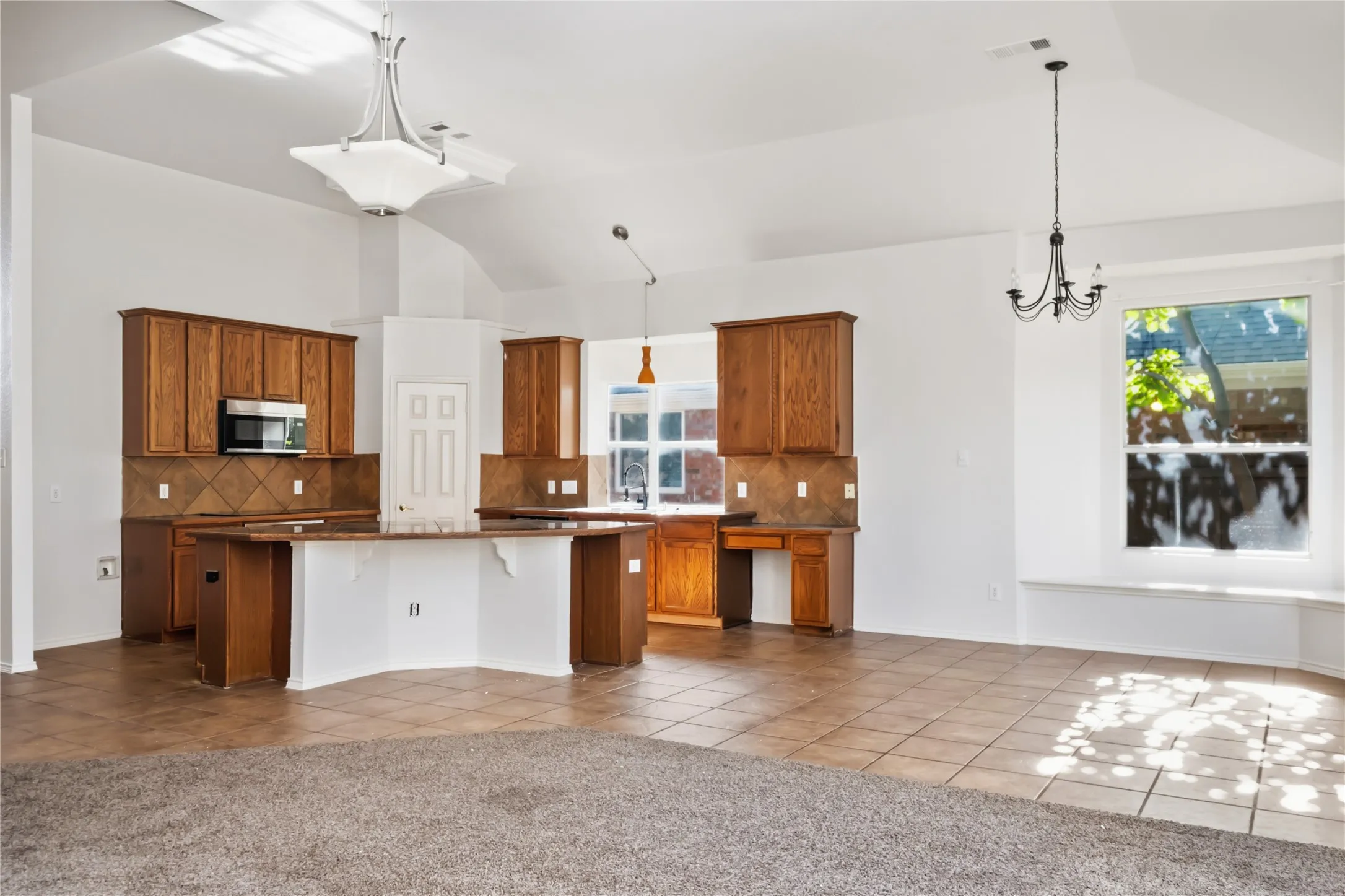 Vaulted ceilings, wood cabinetry, tile flooring, built-in window seating, and a kitchen island with integrated breakfast bar