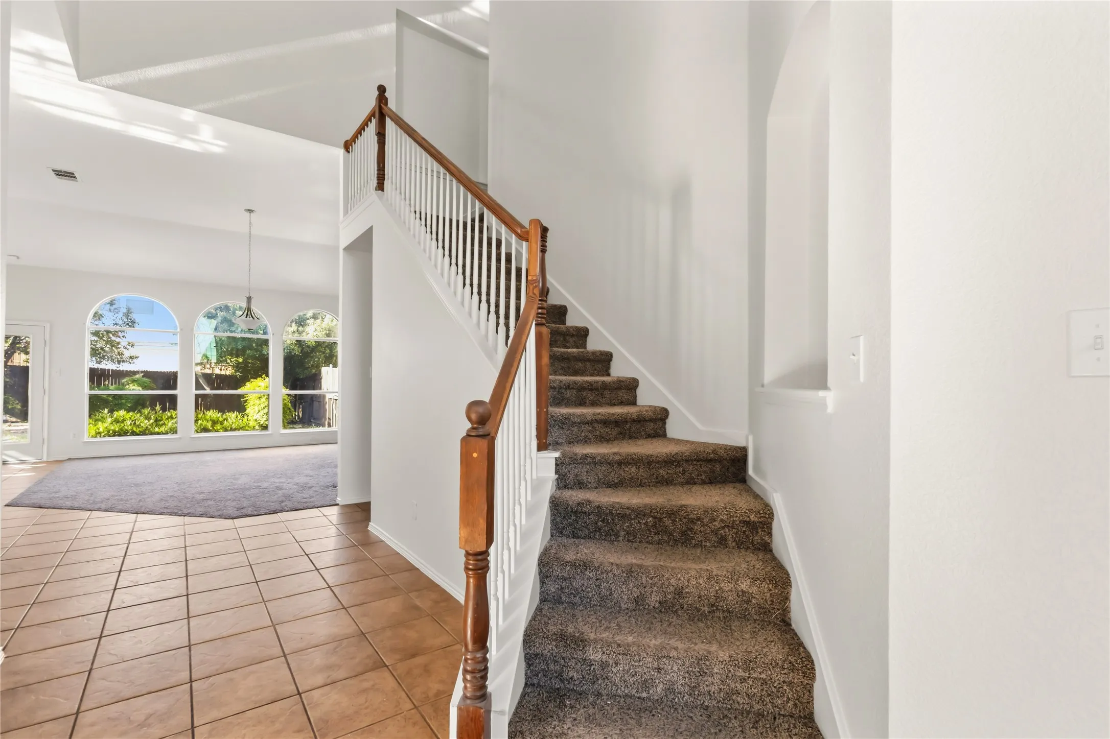 Two-story entry with a wood handrail, white balusters, and a recessed wall niche