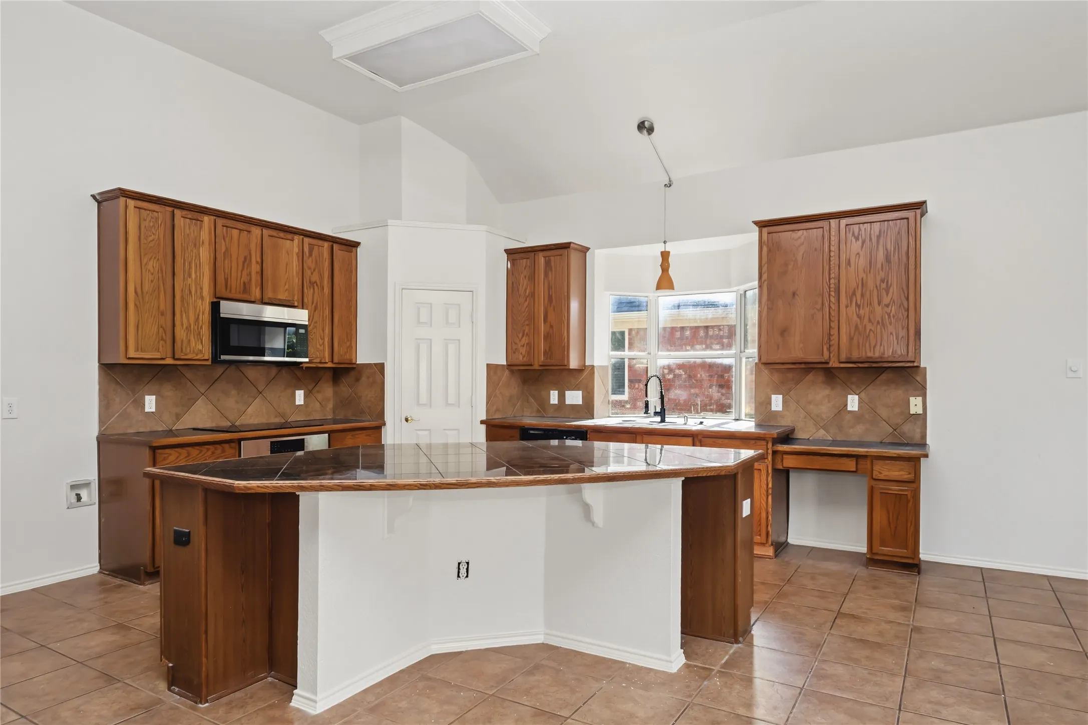 Kitchen featuring a central island with a stone countertop, wood cabinetry, tile flooring, and a tile backsplash