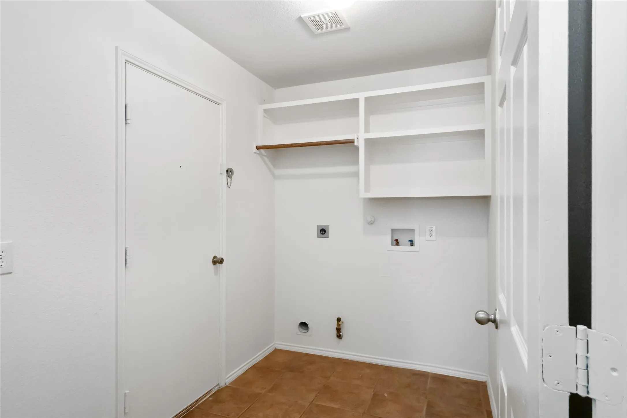 Laundry area featuring tile flooring, built-in shelving, and a hanging rod