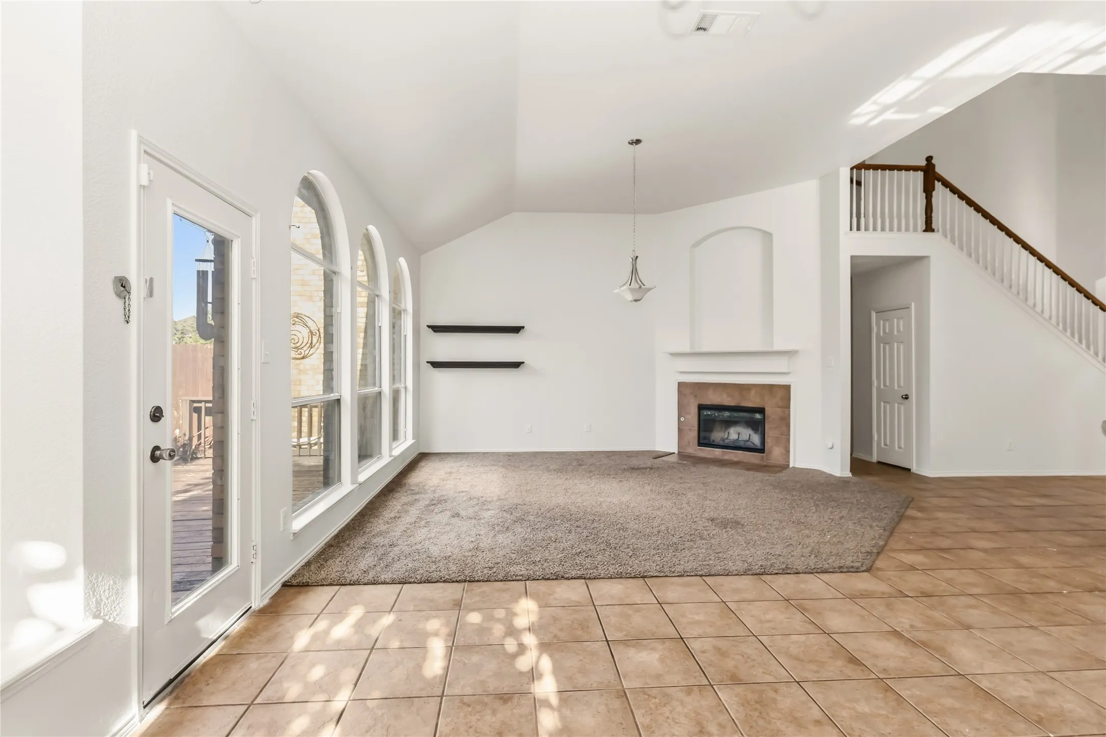Arched windows illuminate the space, complemented by a built-in fireplace with a tile surround