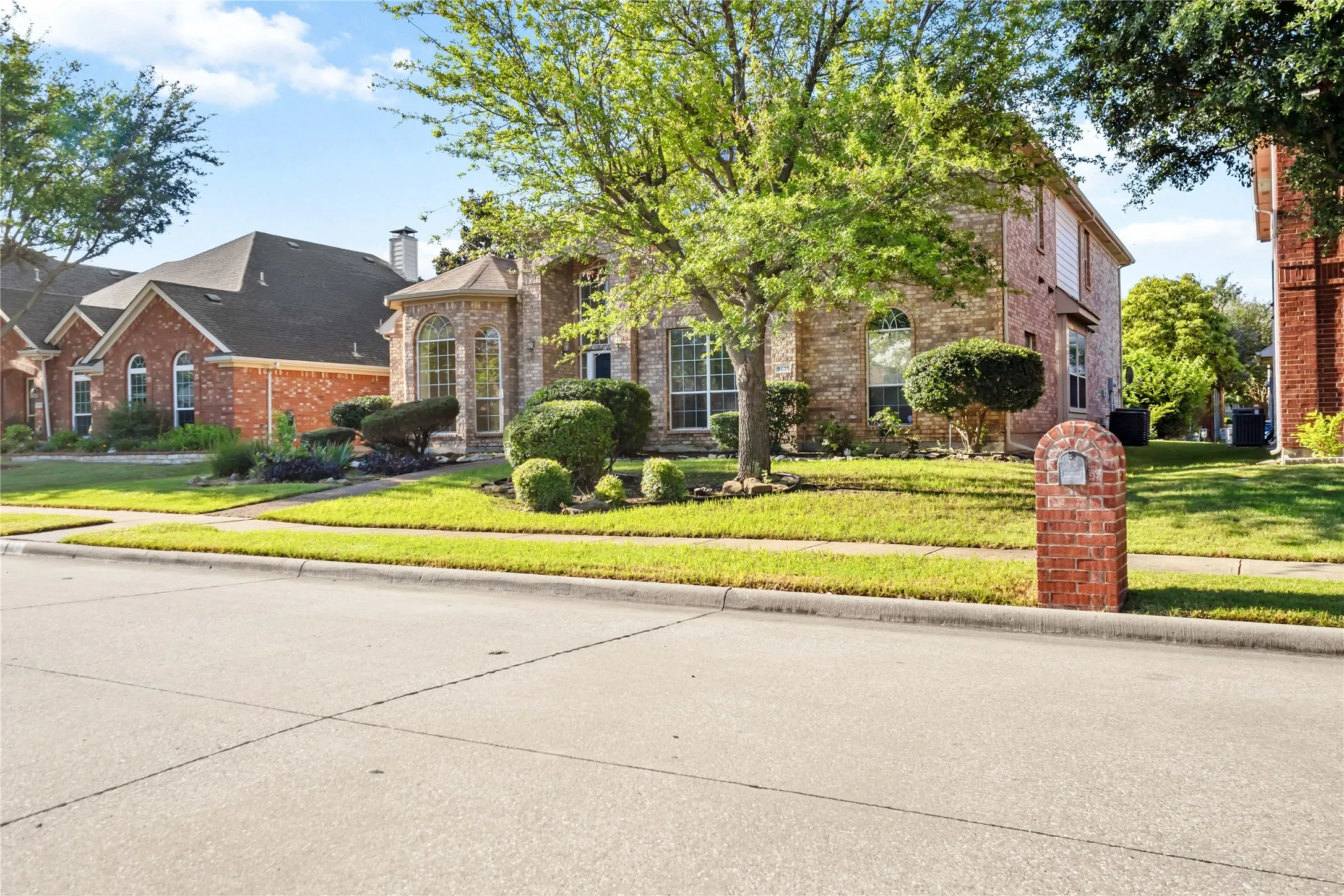 Brick exterior with arched windows, manicured landscaping, and a brick mailbox