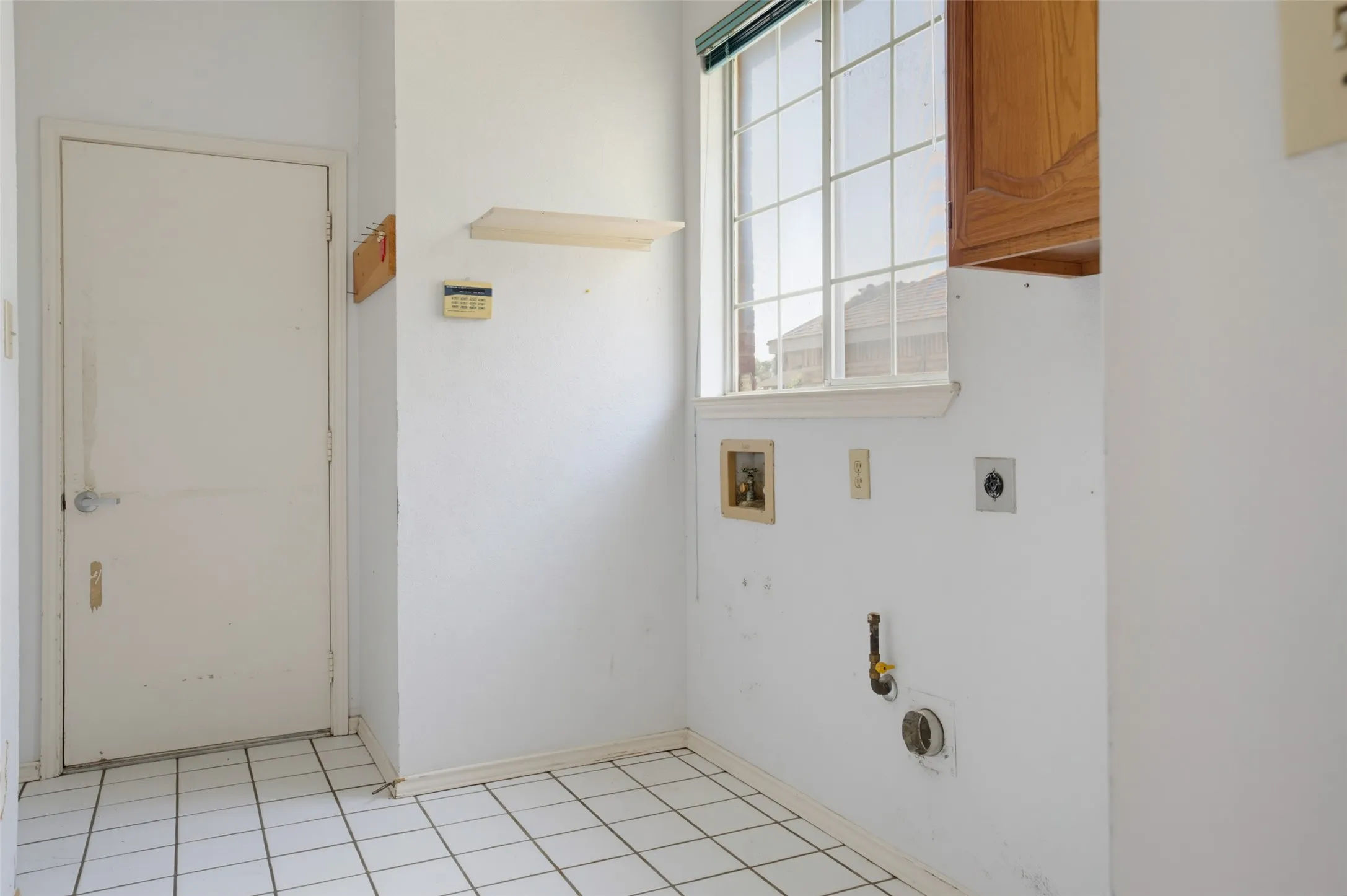 Oversized laundry with space to the left of the garage door with an outlet for for a freezer or add a shelf for a charging station as you come in.