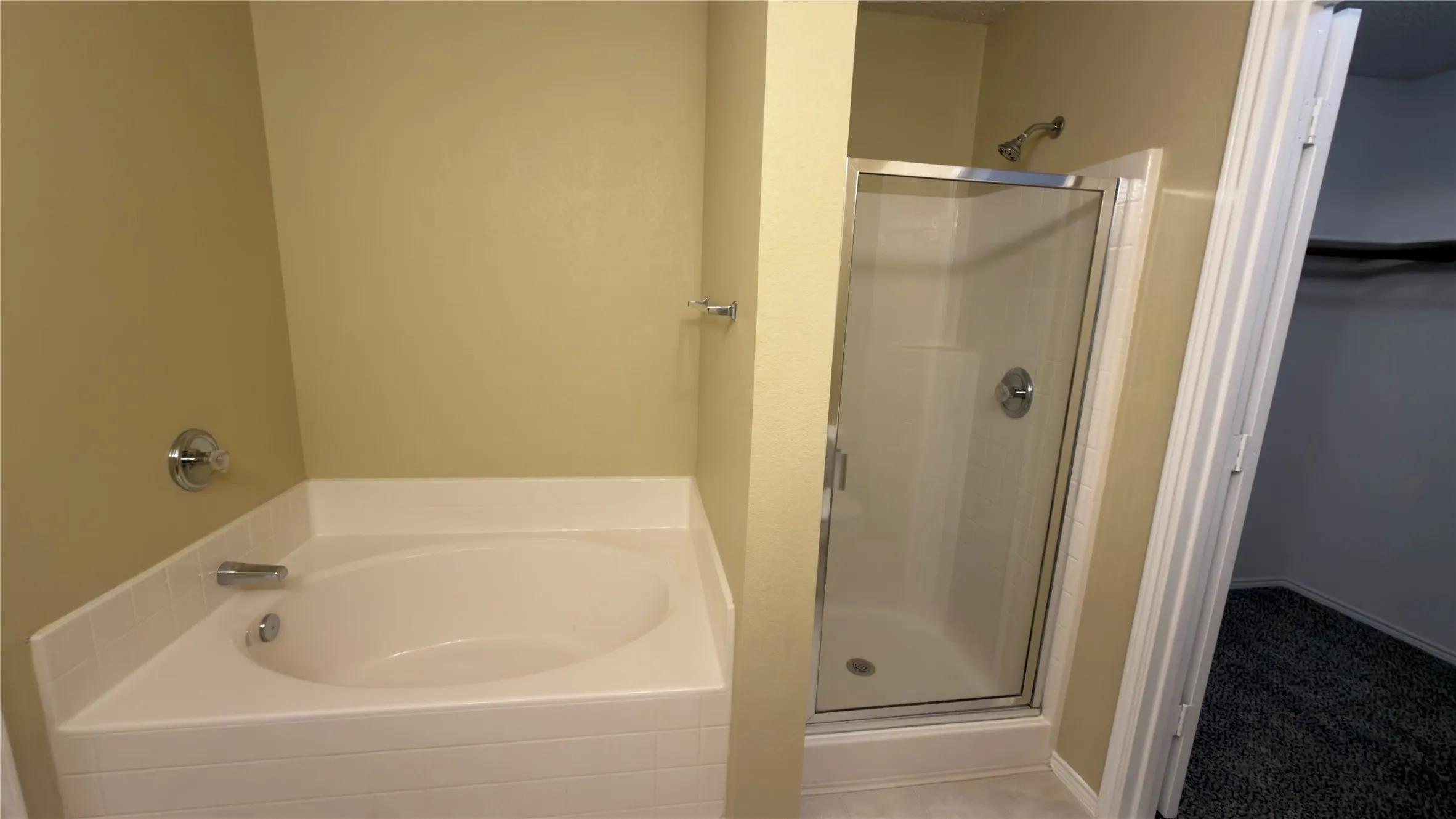 Corner soaking tub and a separate glass-enclosed shower featuring chrome fixtures