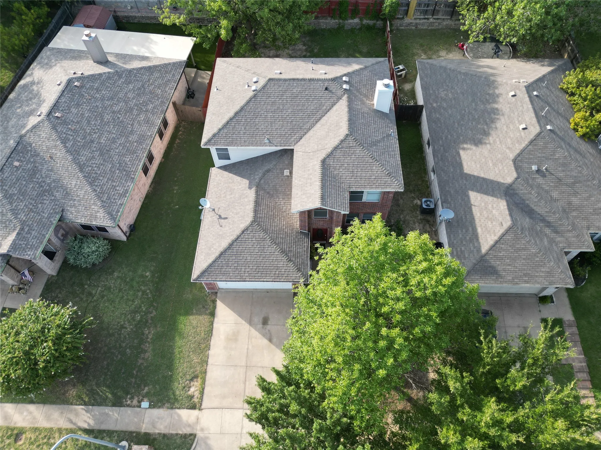 Two-story residence featuring a gray shingle roof and a concrete driveway